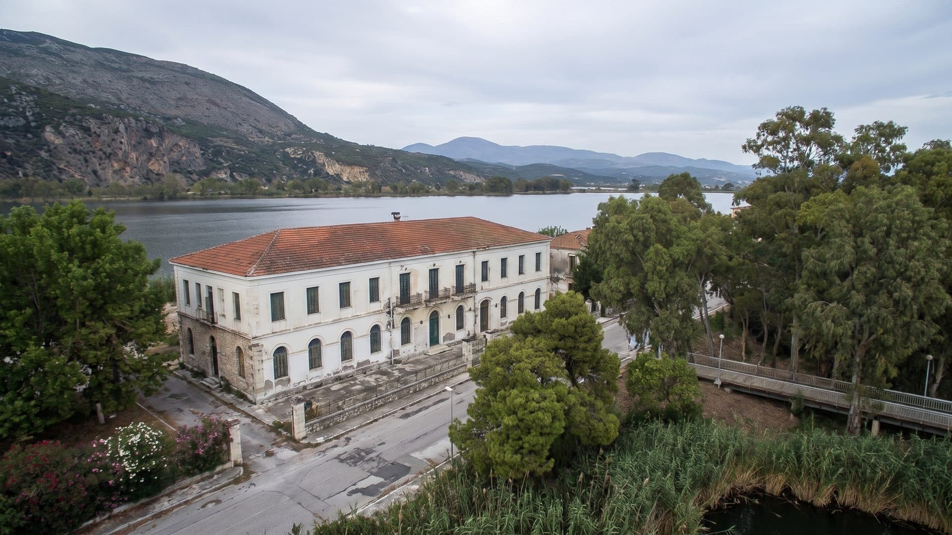 The neoclassical bath house seen from above, standing between the lagoon and the wooded hills.