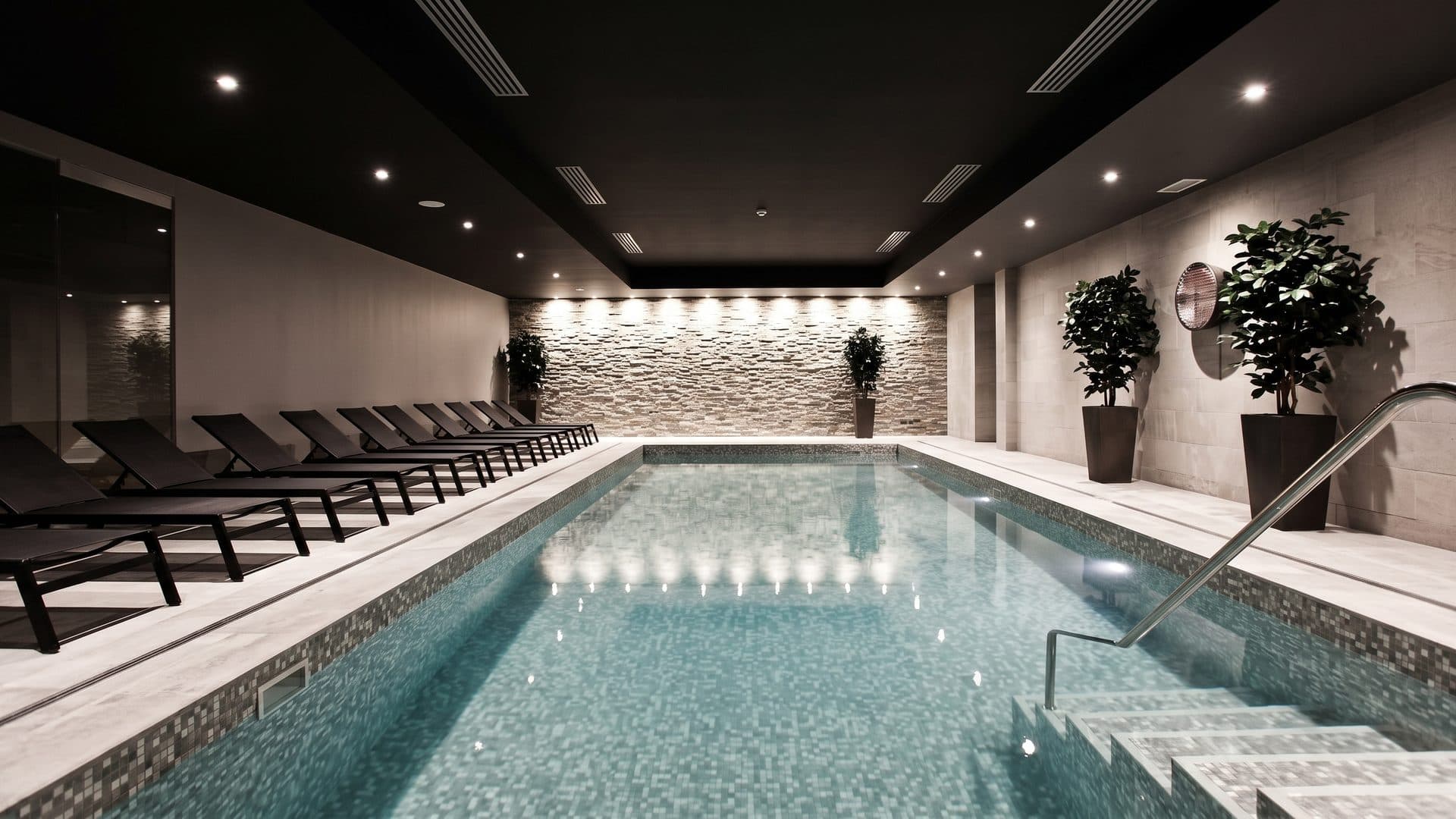The spa pool of Island Spa with loungers along one side under the dark lit ceiling