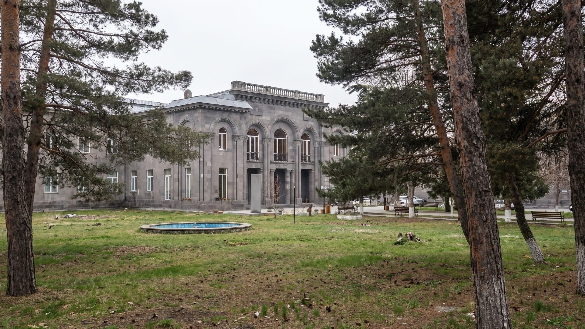 The stone sanatorium building of Jermuk Olympia with its arched windows, among the pines