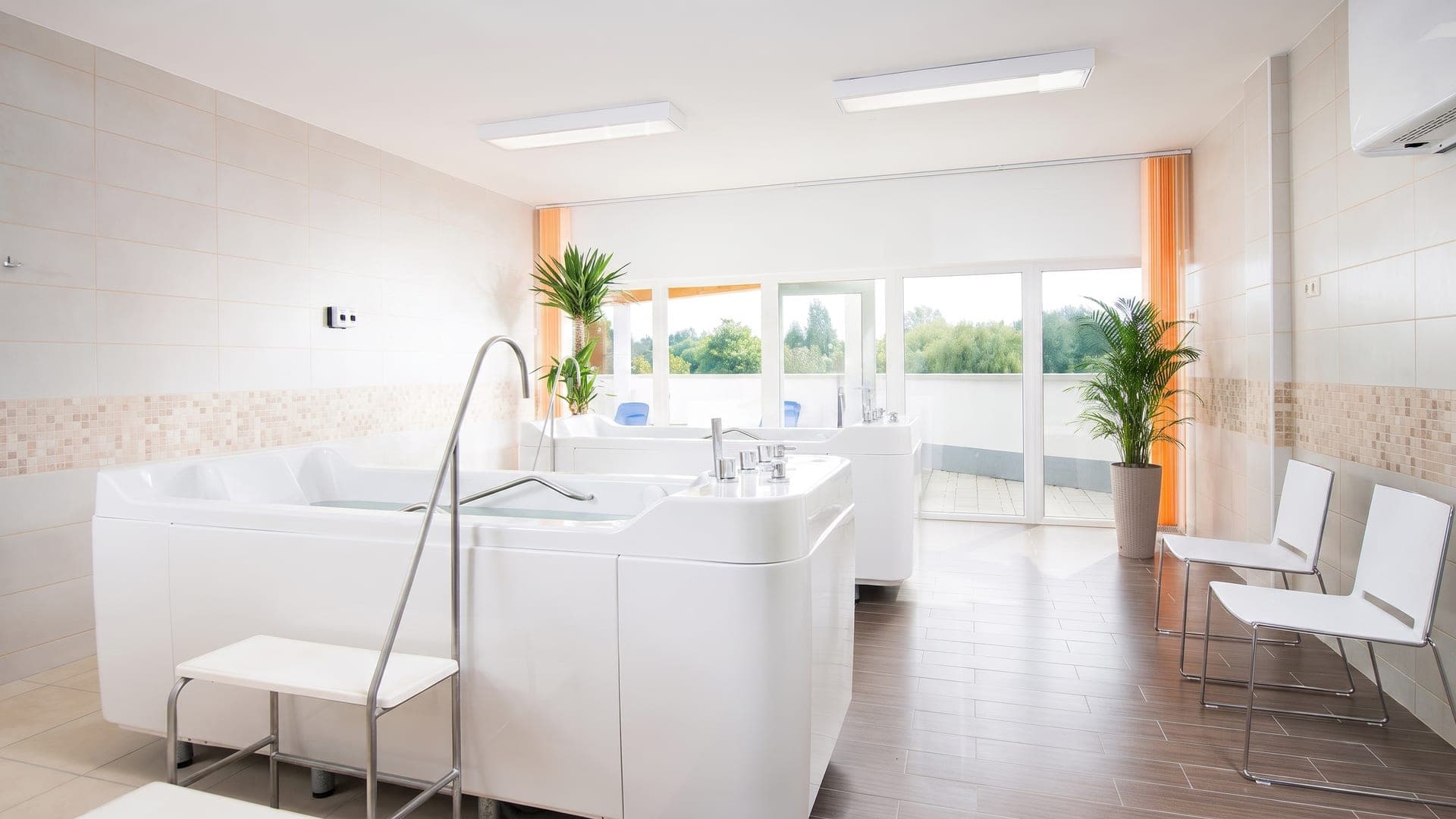 Treatment room with individual white bathing tubs and a window onto the garden