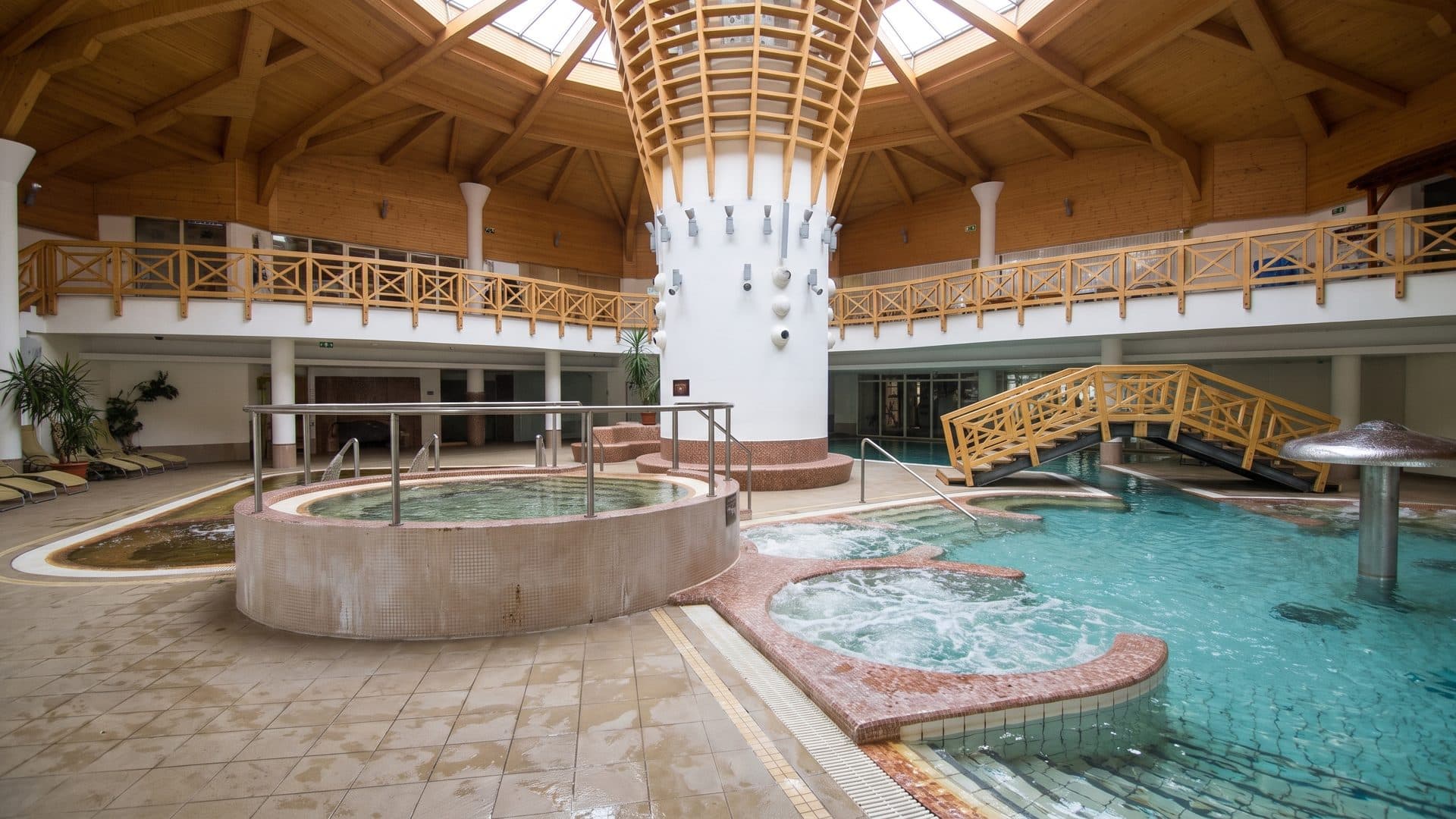 The round hall of the Kamilla thermal bath, its white column feature under a timber-ribbed roof