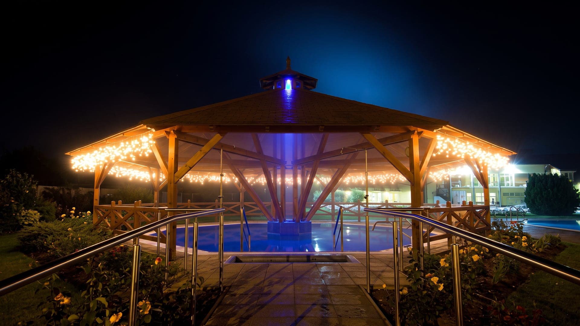 Outdoor pool beneath a lit timber pavilion at night