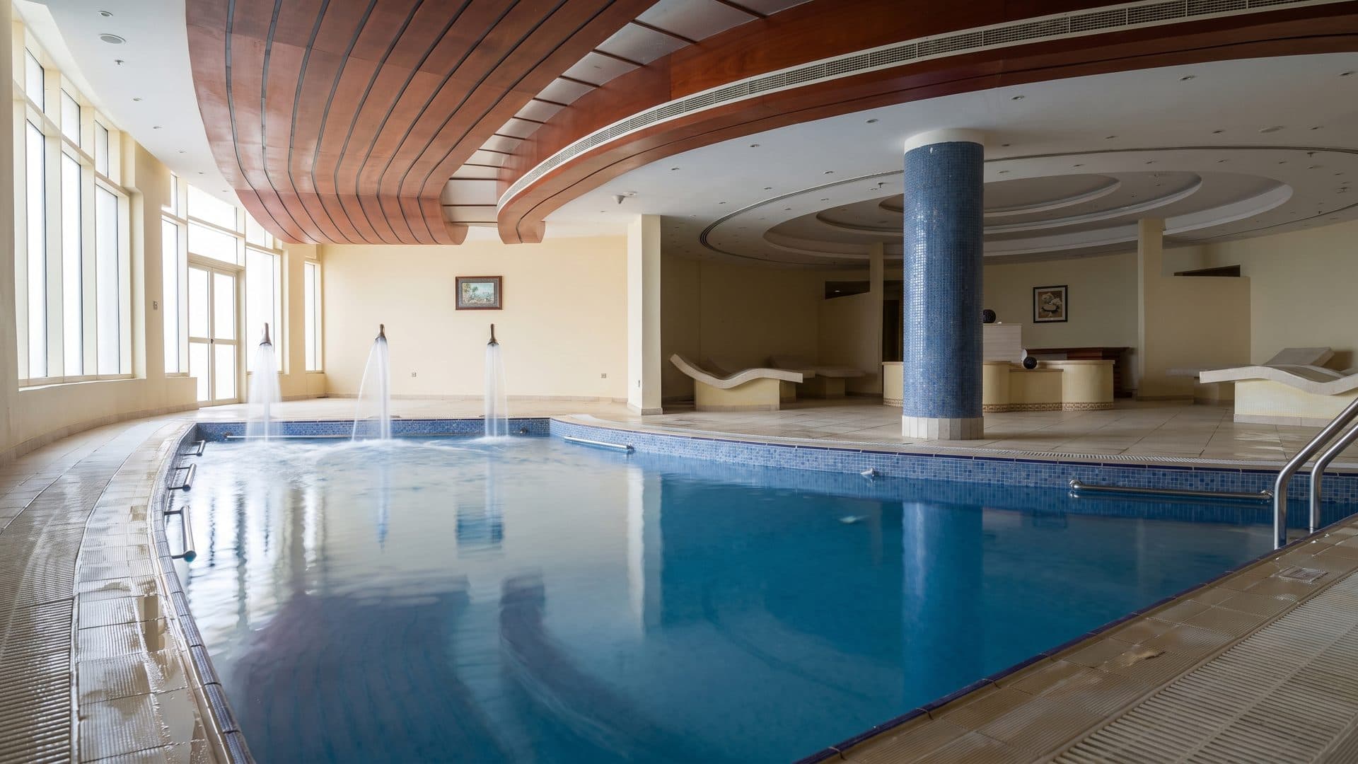The indoor pool at Khatt Springs with its fountain jets, under a curved timber ceiling