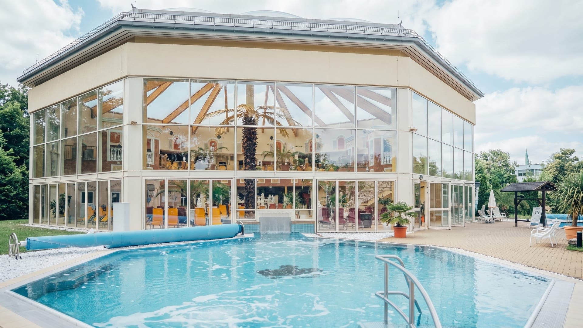 Glass pavilion with a palm inside, beside the outdoor pool