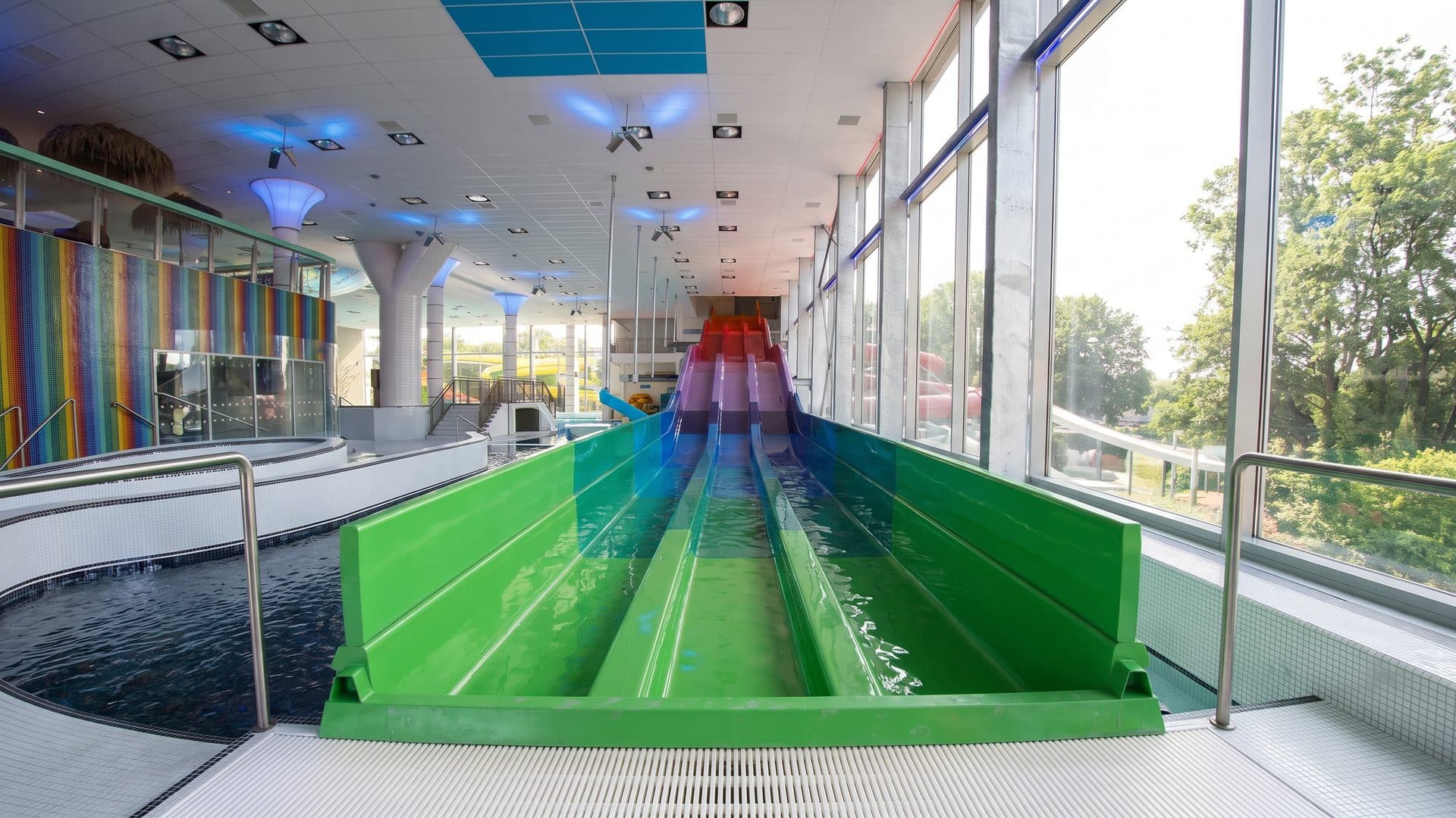 The green water slide of the Cihelna baths above its splash pool by the glazed wall