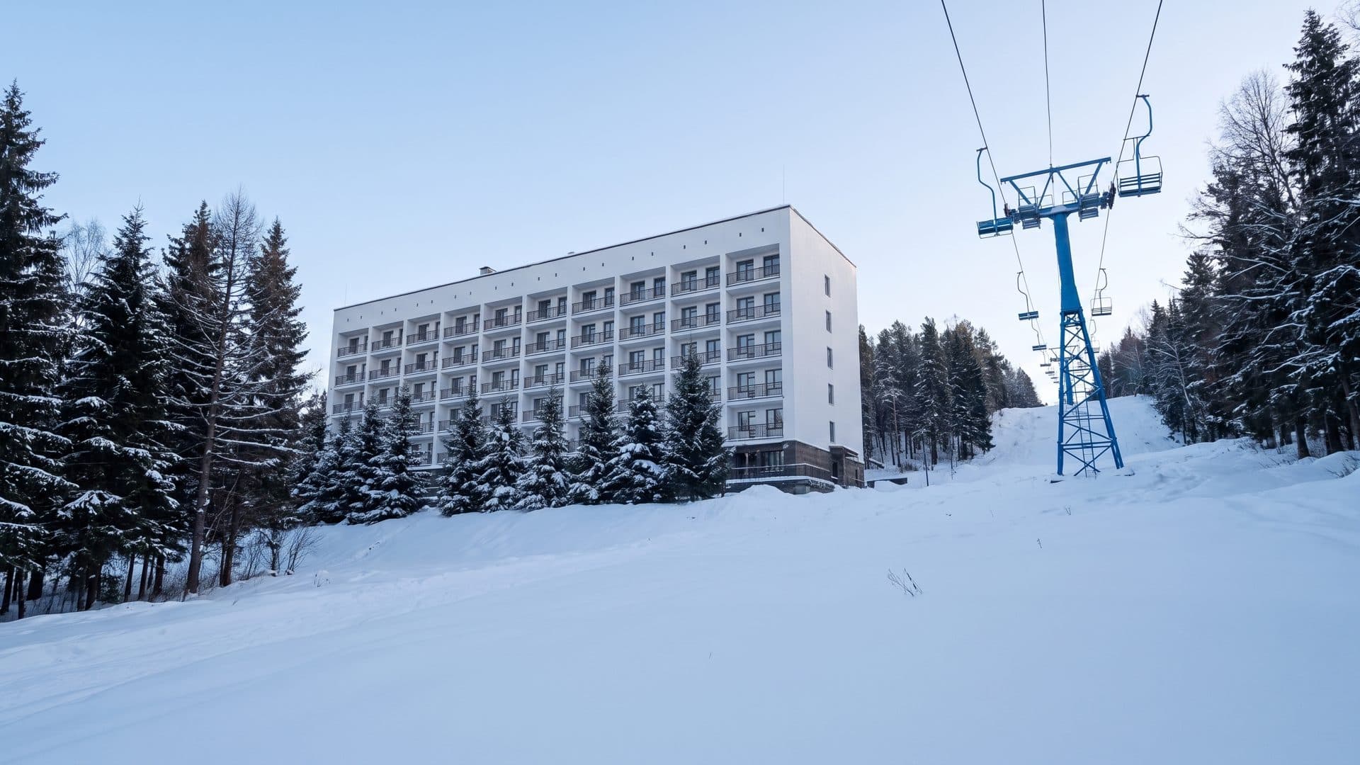 The resort building of Krasnoye Ozero below its chairlift among the snowy conifers