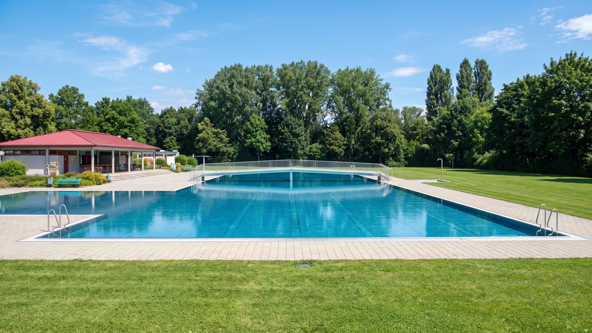 The outdoor pool of the Kürnbergbad in front of its red-roofed pavilion on the lawn