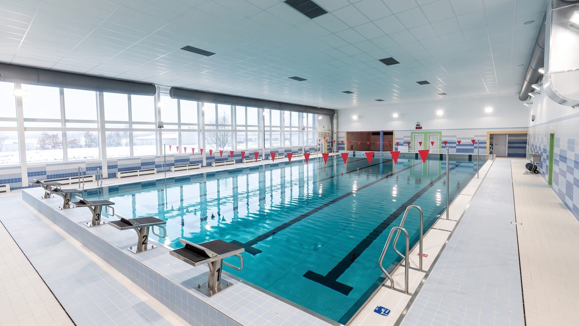 Indoor swimming pool of the spa, lane ropes across the water and a glazed wall along one side.