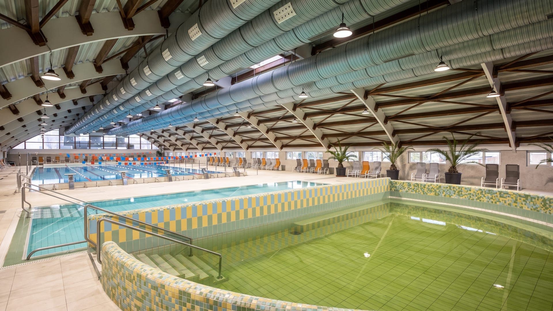 The indoor hall at the Lenti thermal bath, its mosaic-tiled thermal basin of green water beside the lane pool.