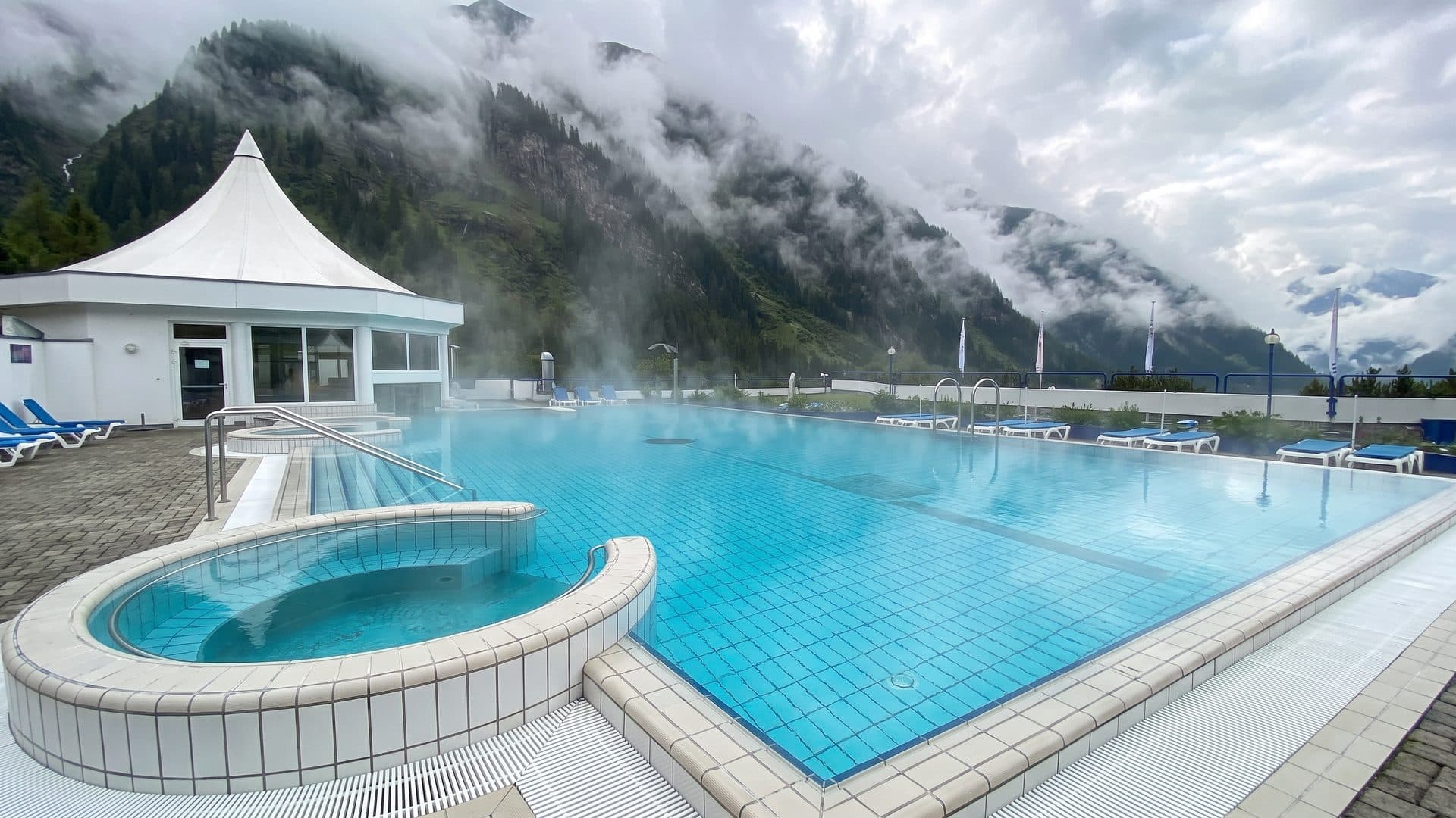 The steaming thermal pool of Ovronnaz with the bath building and the mountain slopes behind
