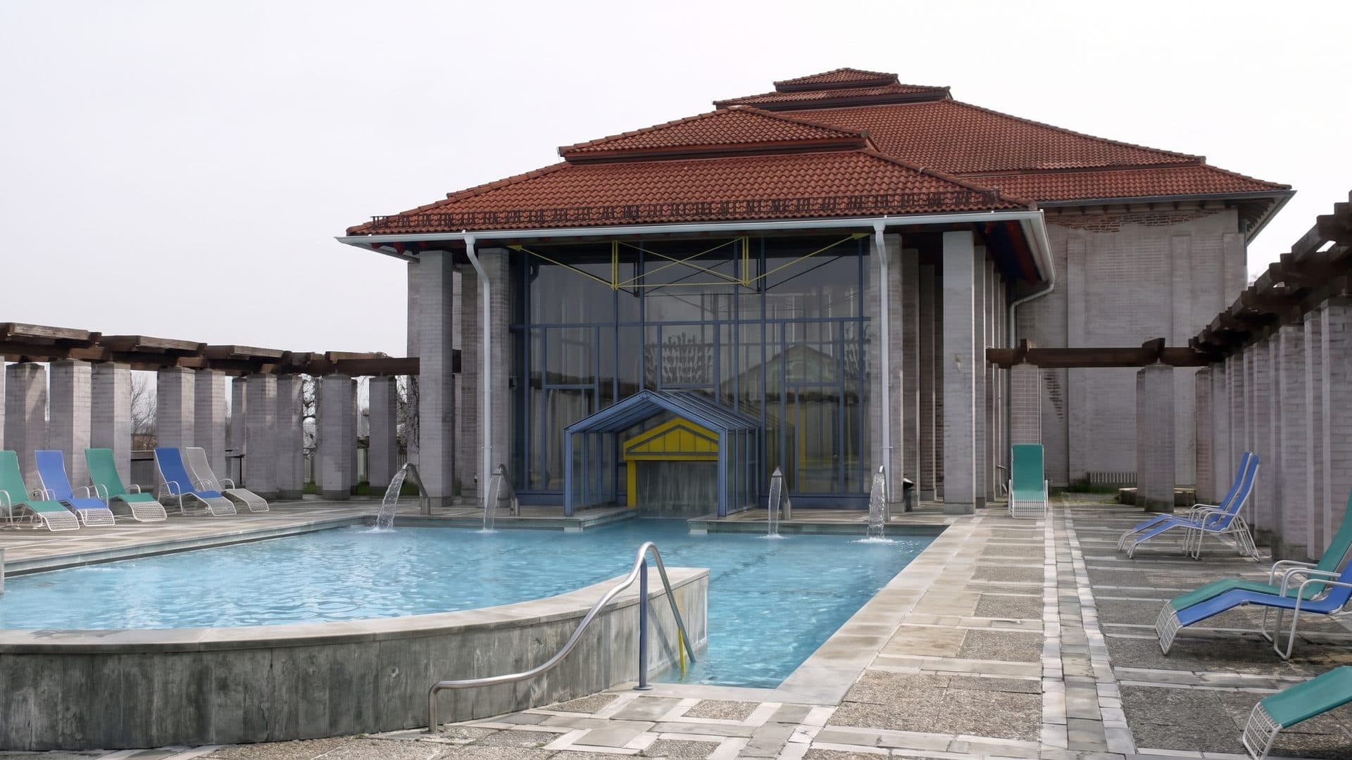 The round outdoor pool at the Limes Thermen in front of the temple-like bath building with its tiled hipped roof