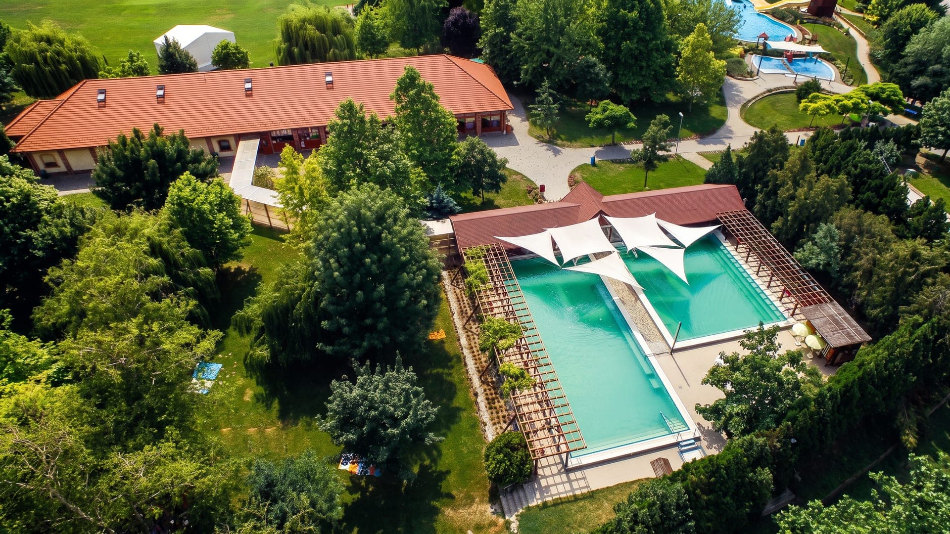 Aerial view of the pools under white sail canopies among trees