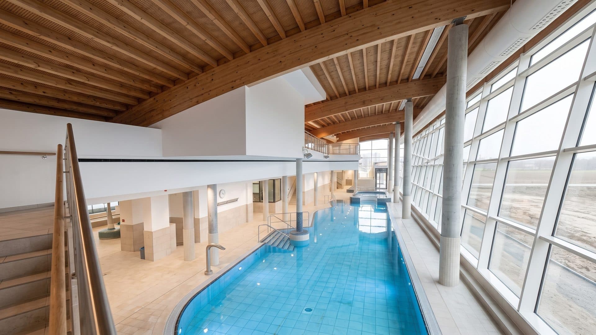 The curved indoor pool of the Meerzeit in Busum under a timber ceiling, beside a glazed wall