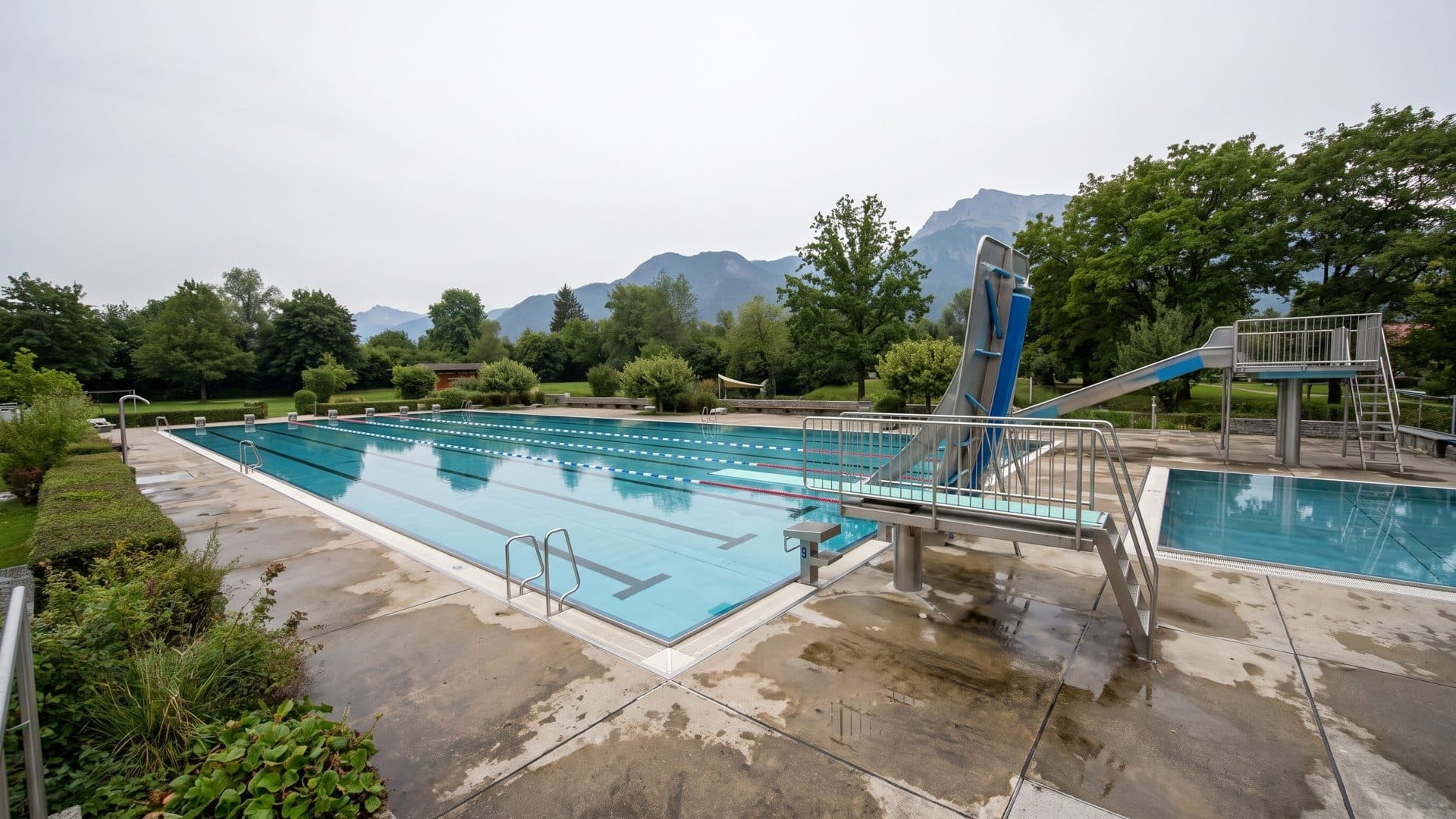 The outdoor lane pool of the Alpinbad Schwarzbach with a diving tower, mountains behind Bad Reichenhall