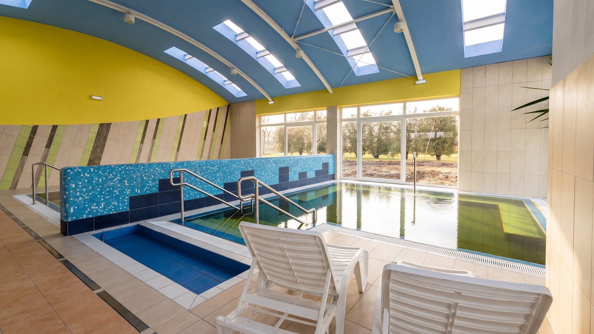 The indoor thermal pool at the bath in Mezotur, with a wall of windows onto the park.