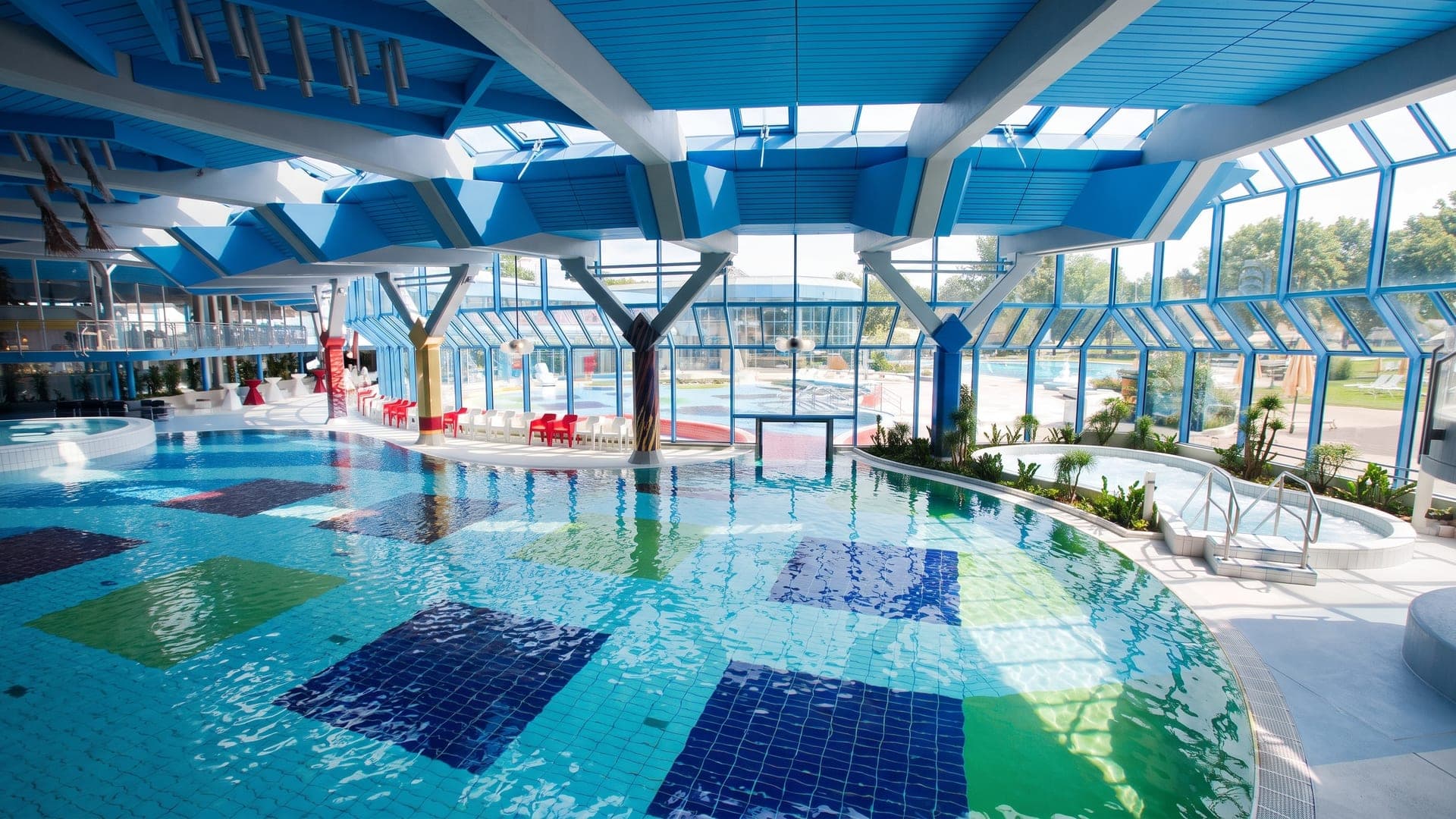 Pool hall under a blue steel frame, with a coloured mosaic floor
