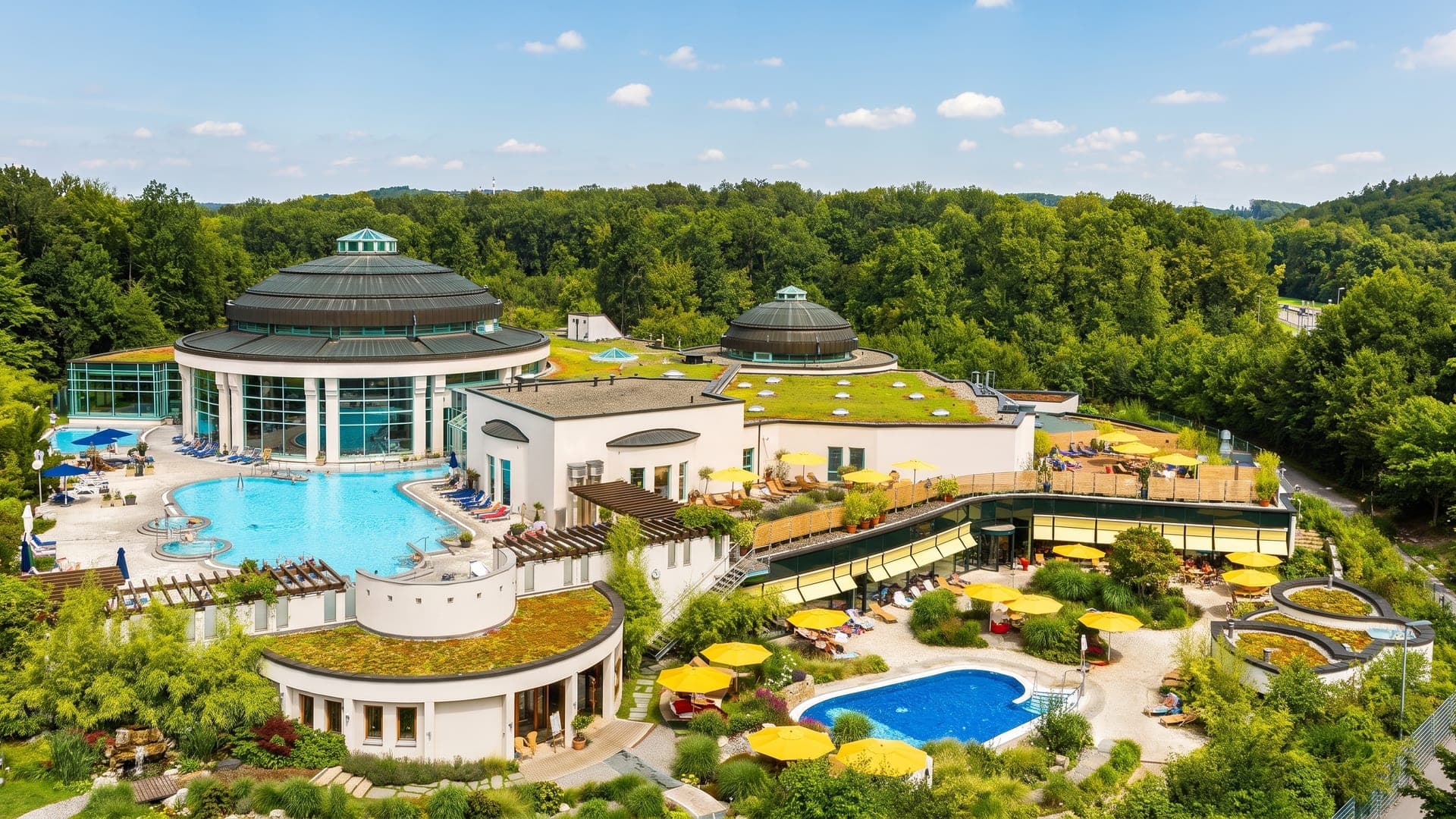 The Mineraltherme in Boeblingen seen from the air, its terraced pools and yellow parasols set in woodland.