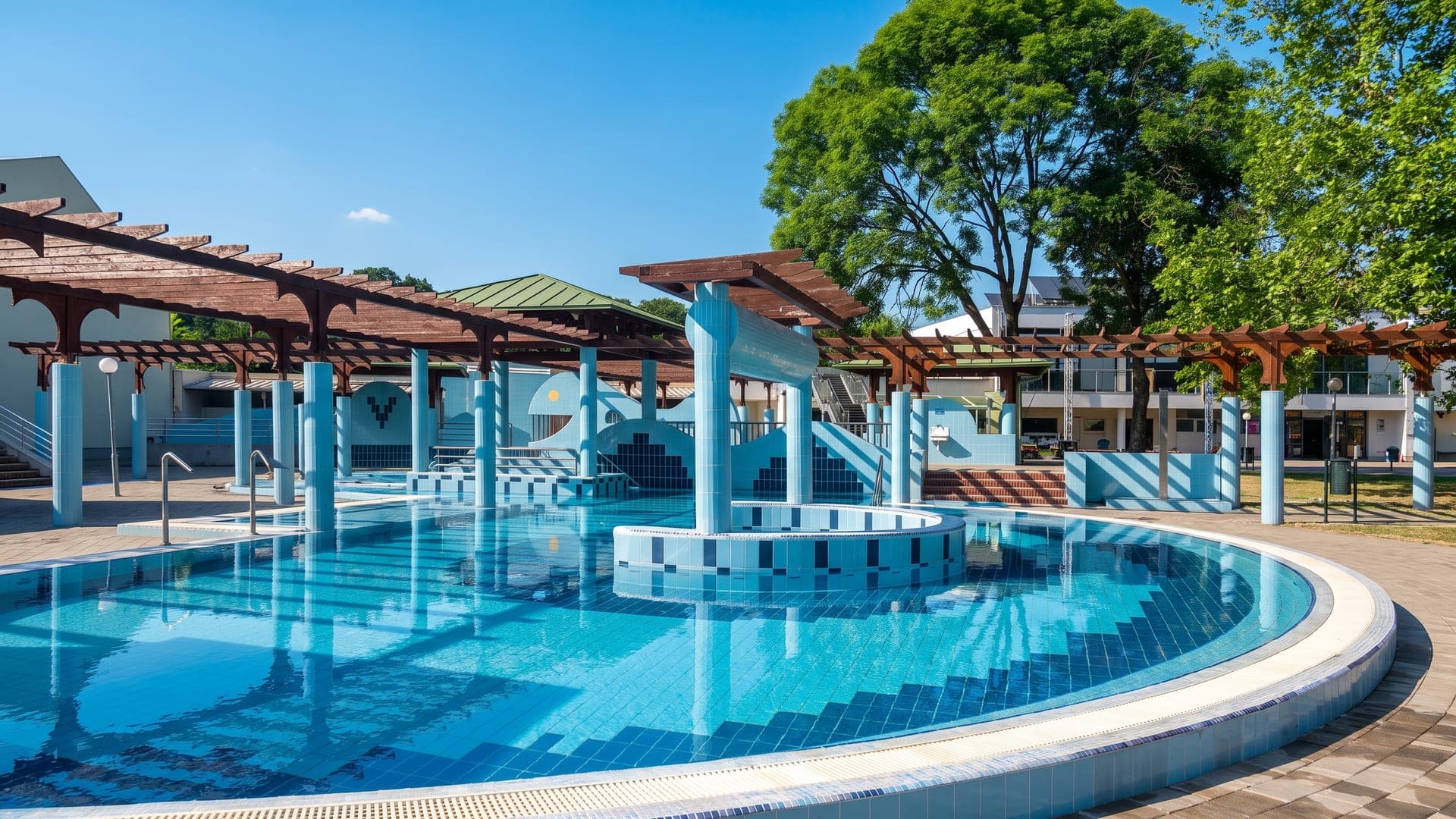 The outdoor pool at the Mohacs baths, with timber pergolas along the terrace and trees behind.