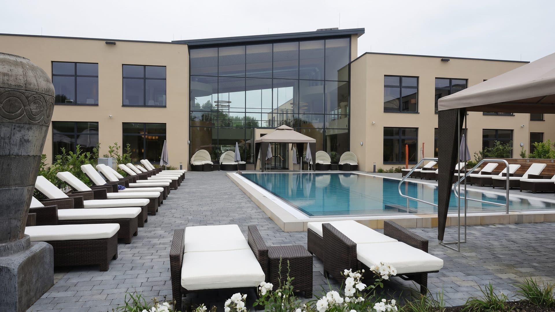 The monte mare baths with the loungers set out along the outdoor pool by the glazed building