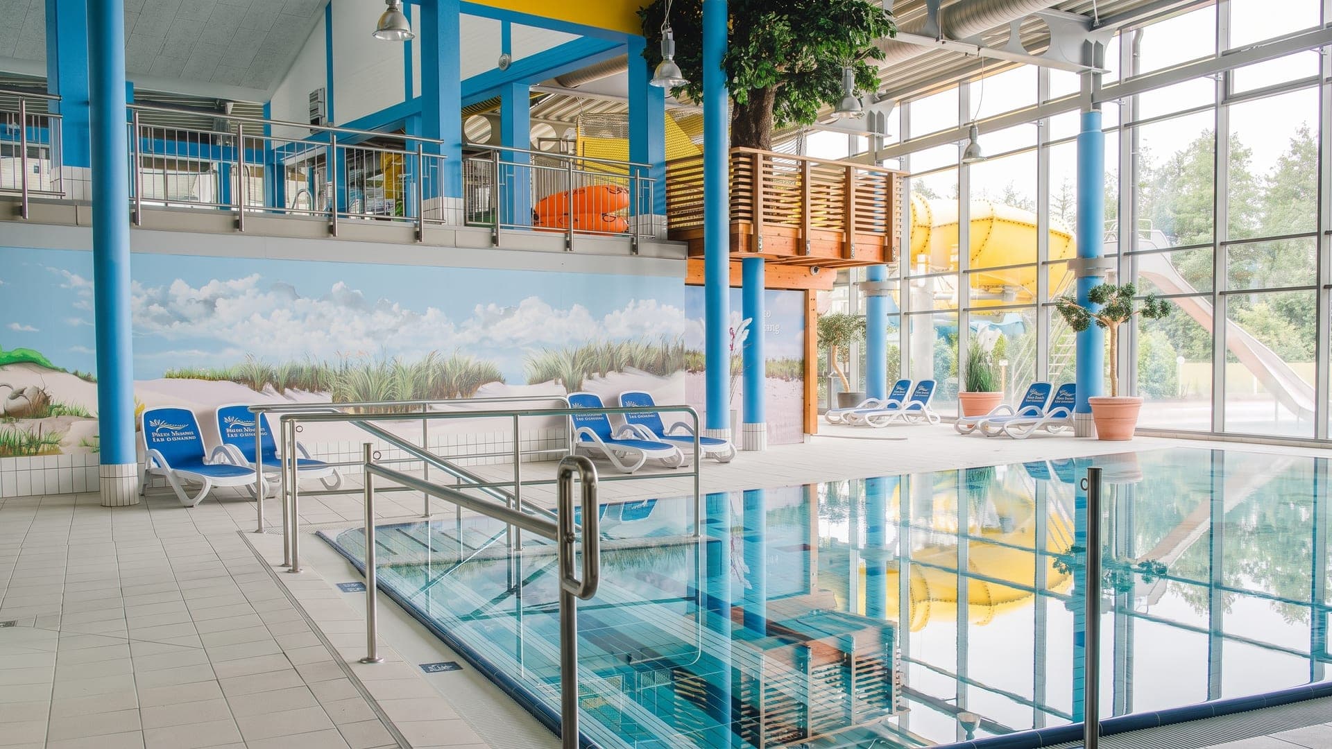 Indoor pool hall with blue columns and a painted dune mural