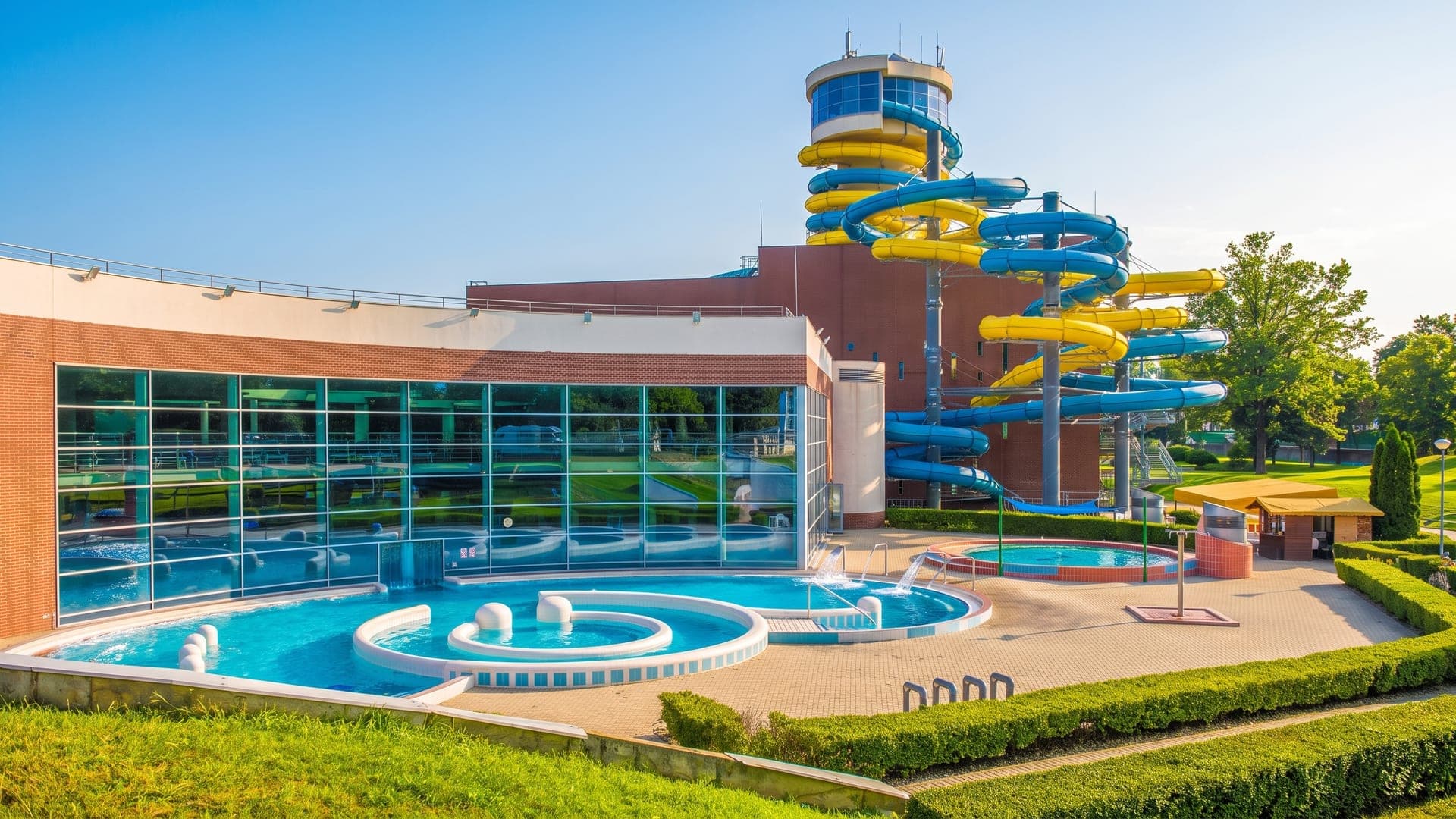 The Napfenyfurdo Aquapolis in Szeged, its slide tower and outdoor pools beside the glass hall.