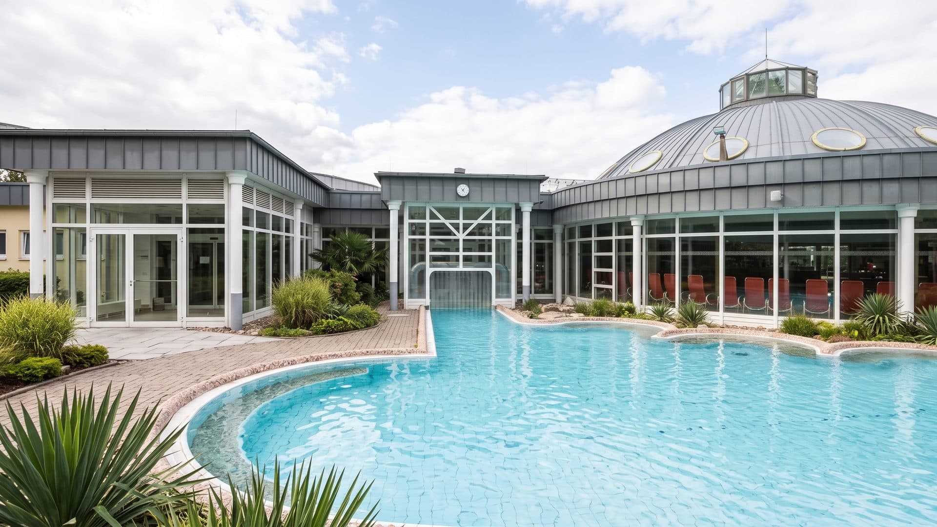 Outdoor pool in front of the round glass hall of the baths under its shallow dome.