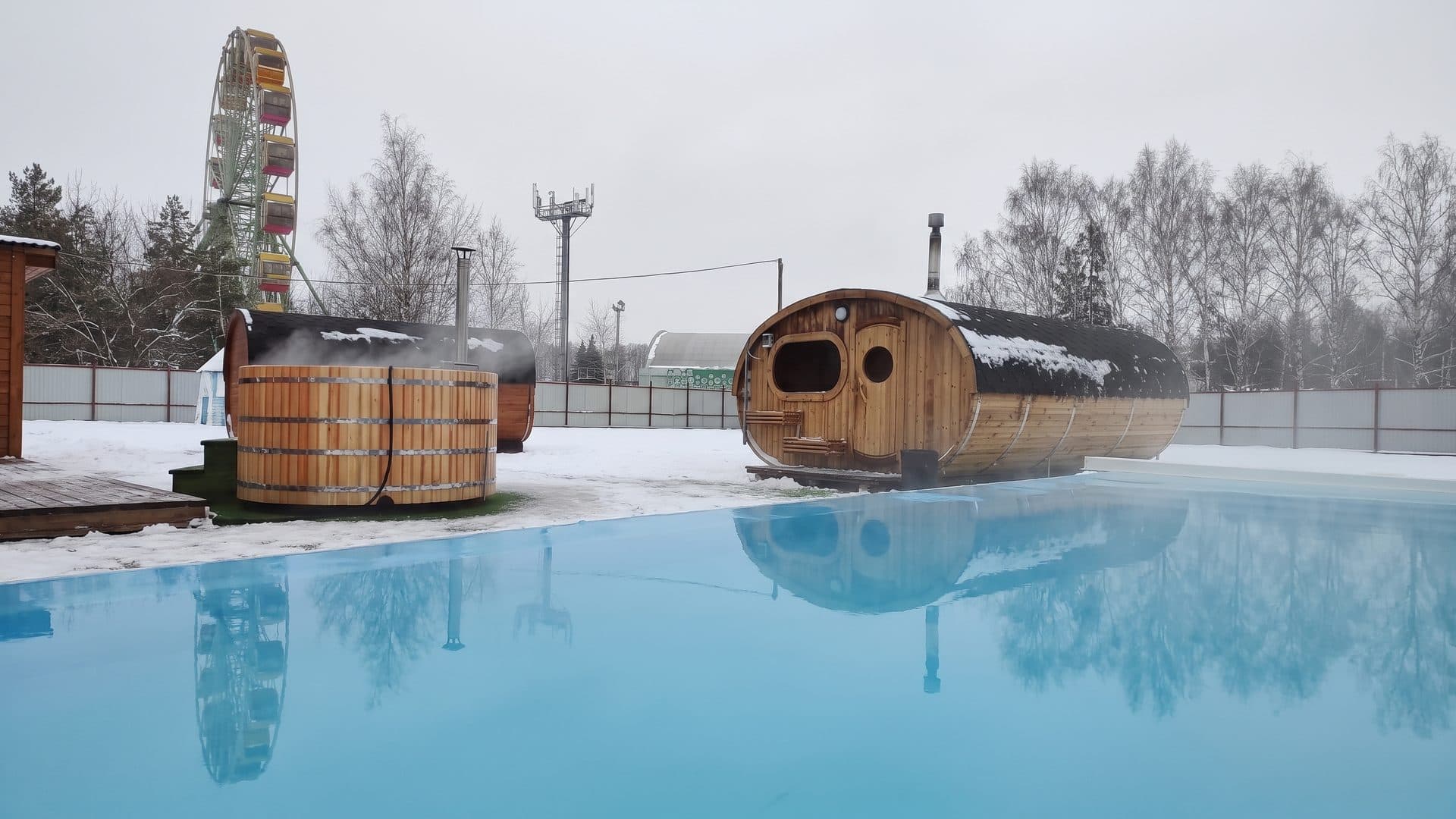The timber hot tubs and barrel sauna of the Nizhnekamsk baths beside a steaming pool in the snow