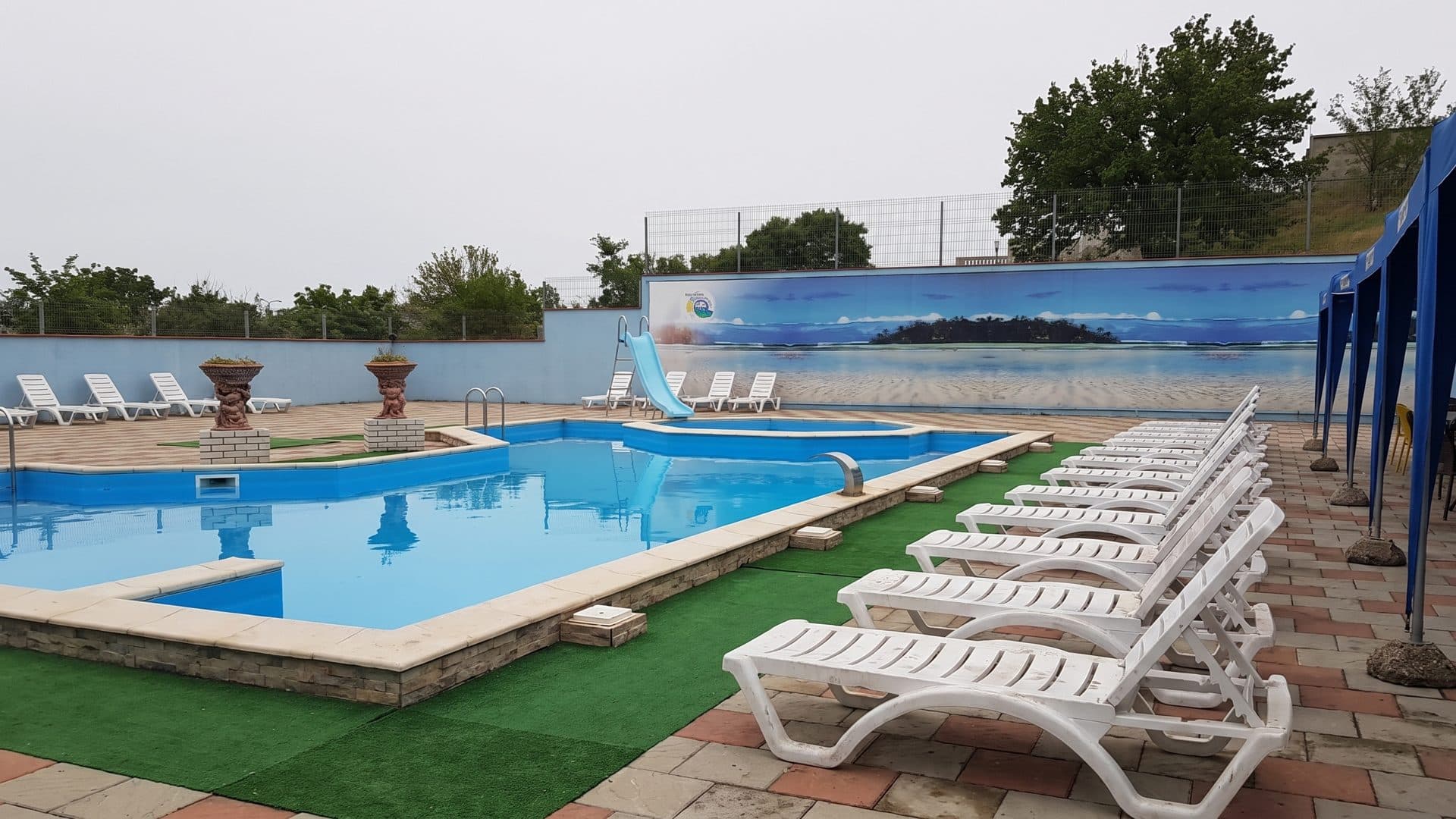 The outdoor pool at Nufarul Alb in Cahul, its blue slide and row of loungers along the water
