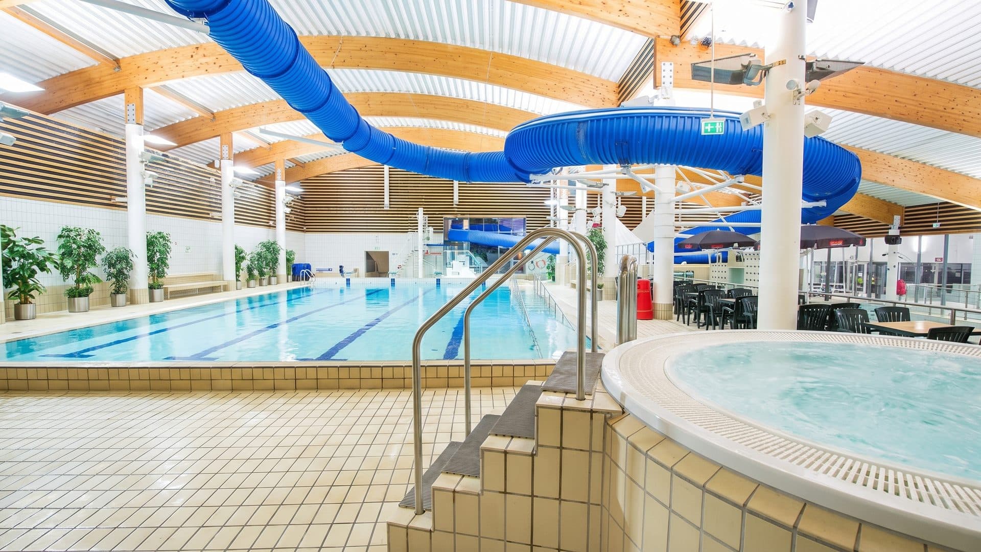 The whirlpool basin of the Østfoldbadet below its blue slides under the timber roof