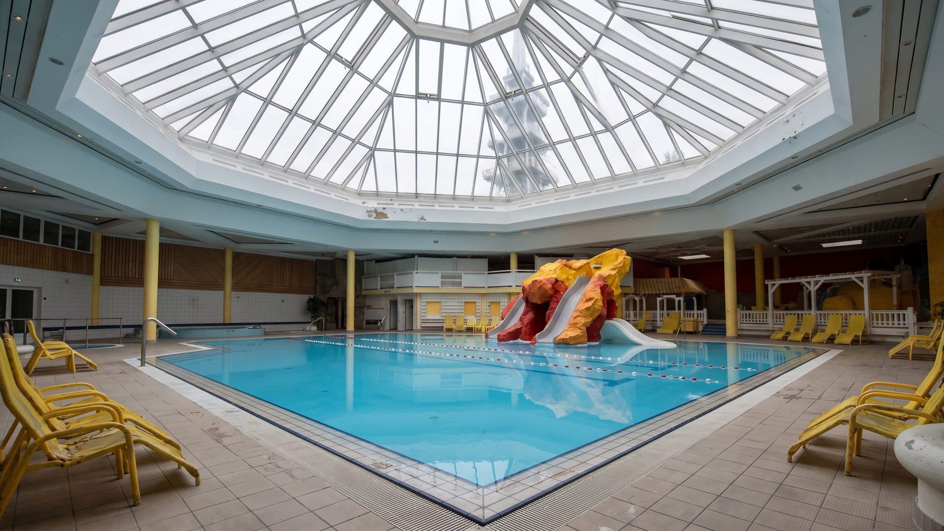The pool under the glass pyramid roof of the Ostseetherme, with the water slide entering the water at the far side