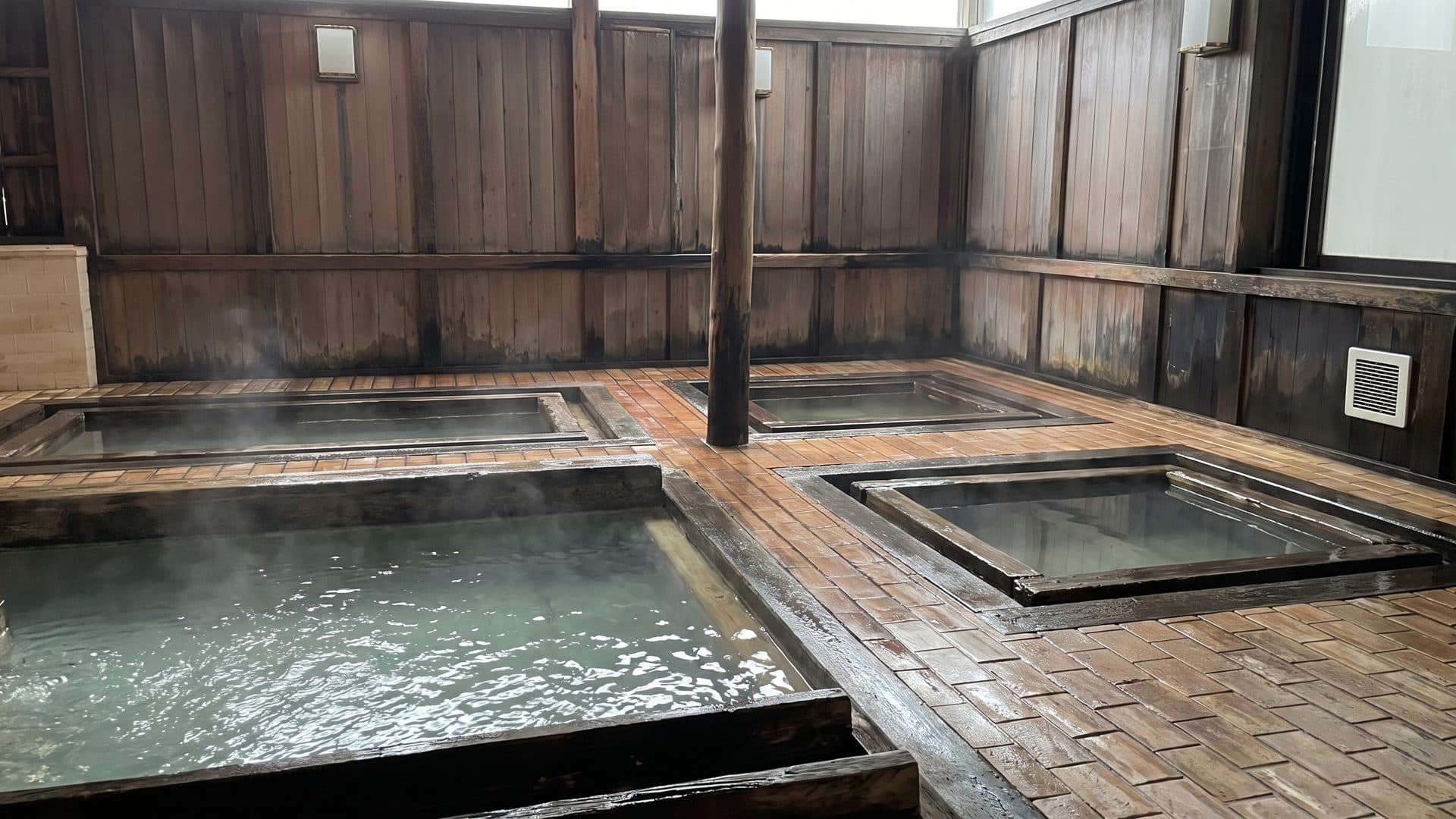 The timber bath house at Otaki no Yu in Kusatsu, its row of wooden tubs on a plank floor