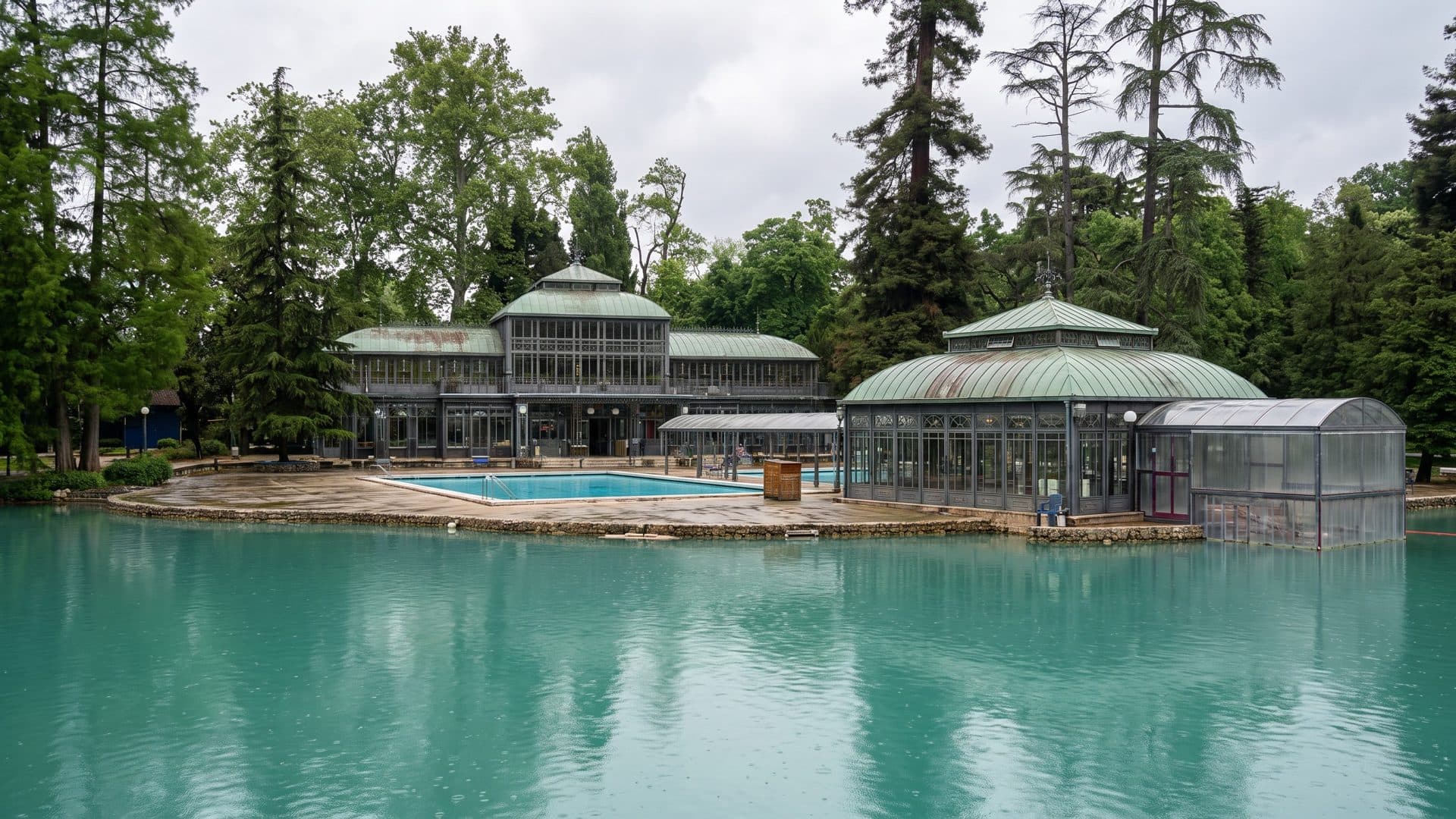 The thermal lake in a wooded park, with the green-roofed pavilions and a pool along its shore