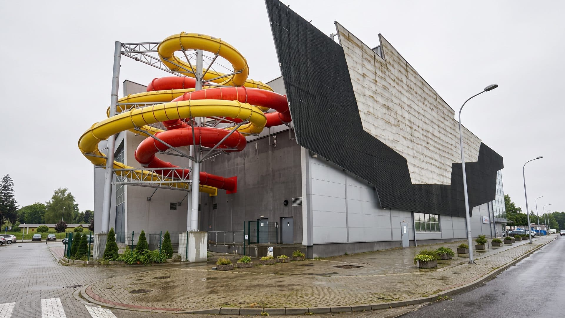 The Chelm water park building with yellow and red slides wound around a tower beside the dark facade