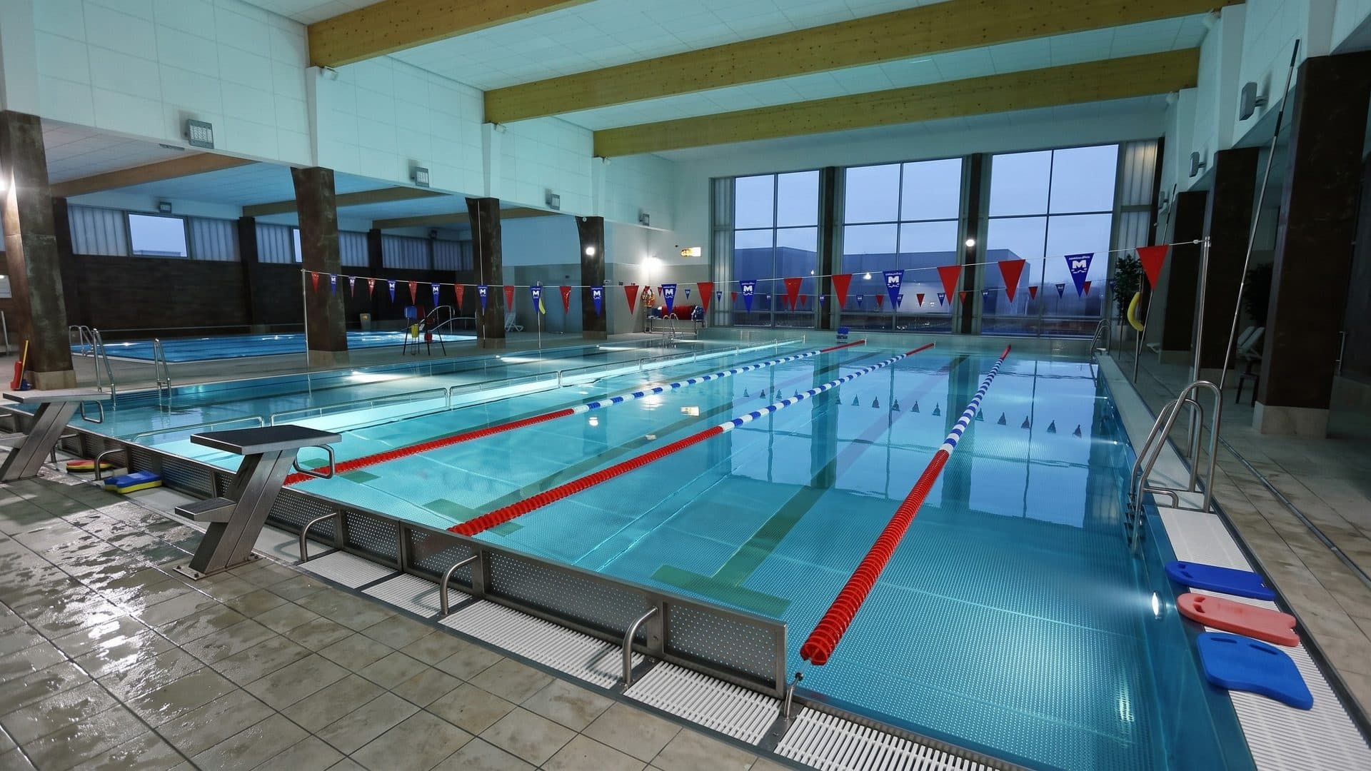 The lane pool of Park Wodny Libiaz with red lane ropes and a starting block, under a panelled ceiling