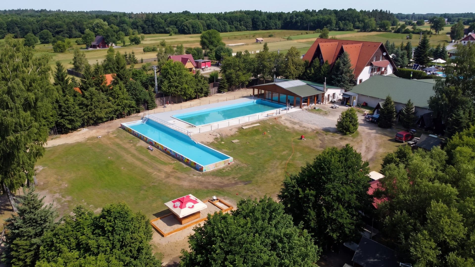 Perla Vlahitei seen from the air: the thermal pools and pavilions among fields and woods