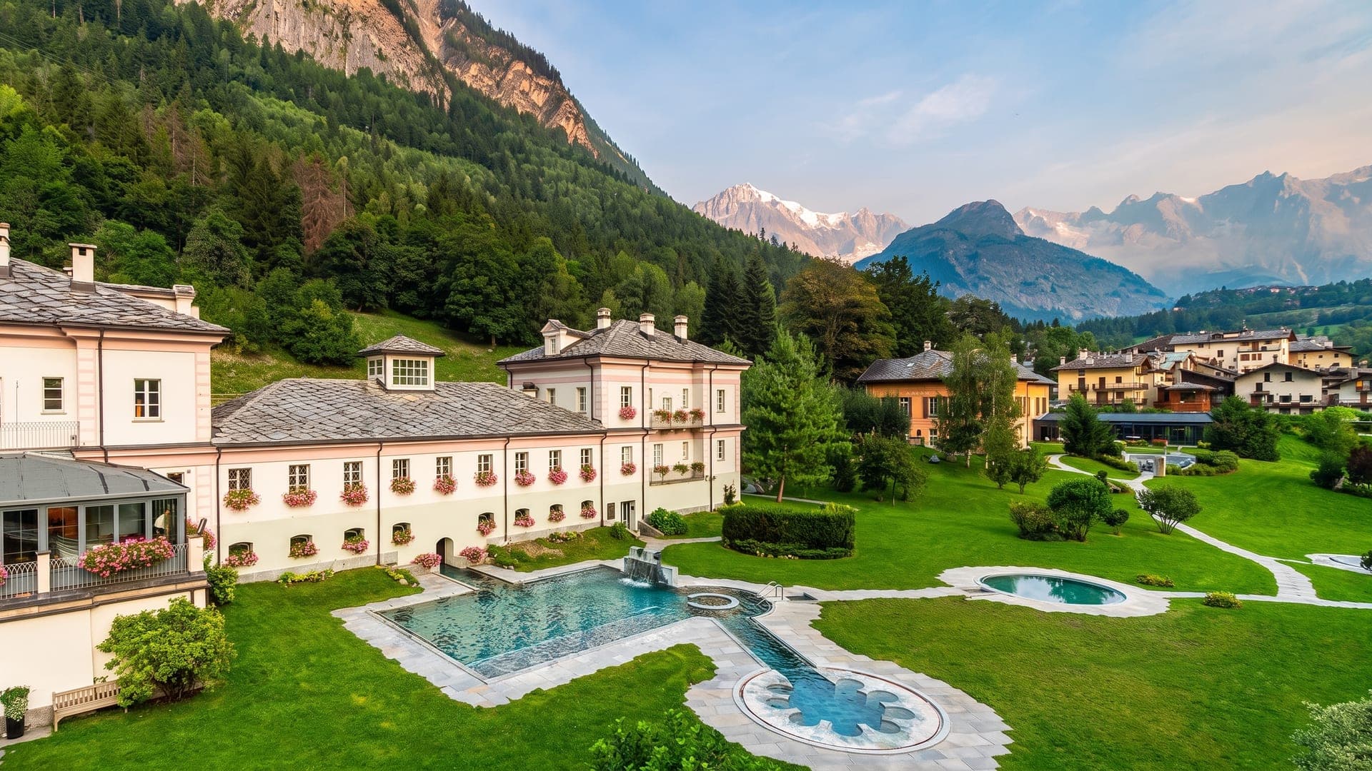 The historic bath house at QC Terme Pre Saint Didier, its garden pools below and the Mont Blanc massif behind.