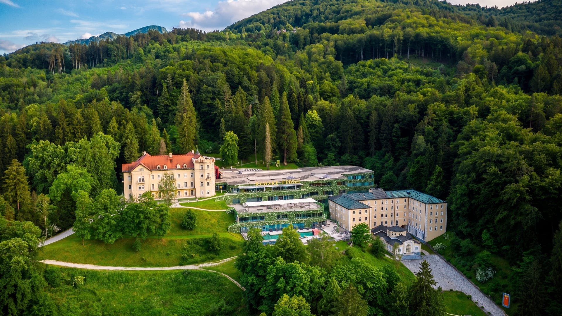 Aerial view of the white villa and spa buildings in a wooded valley
