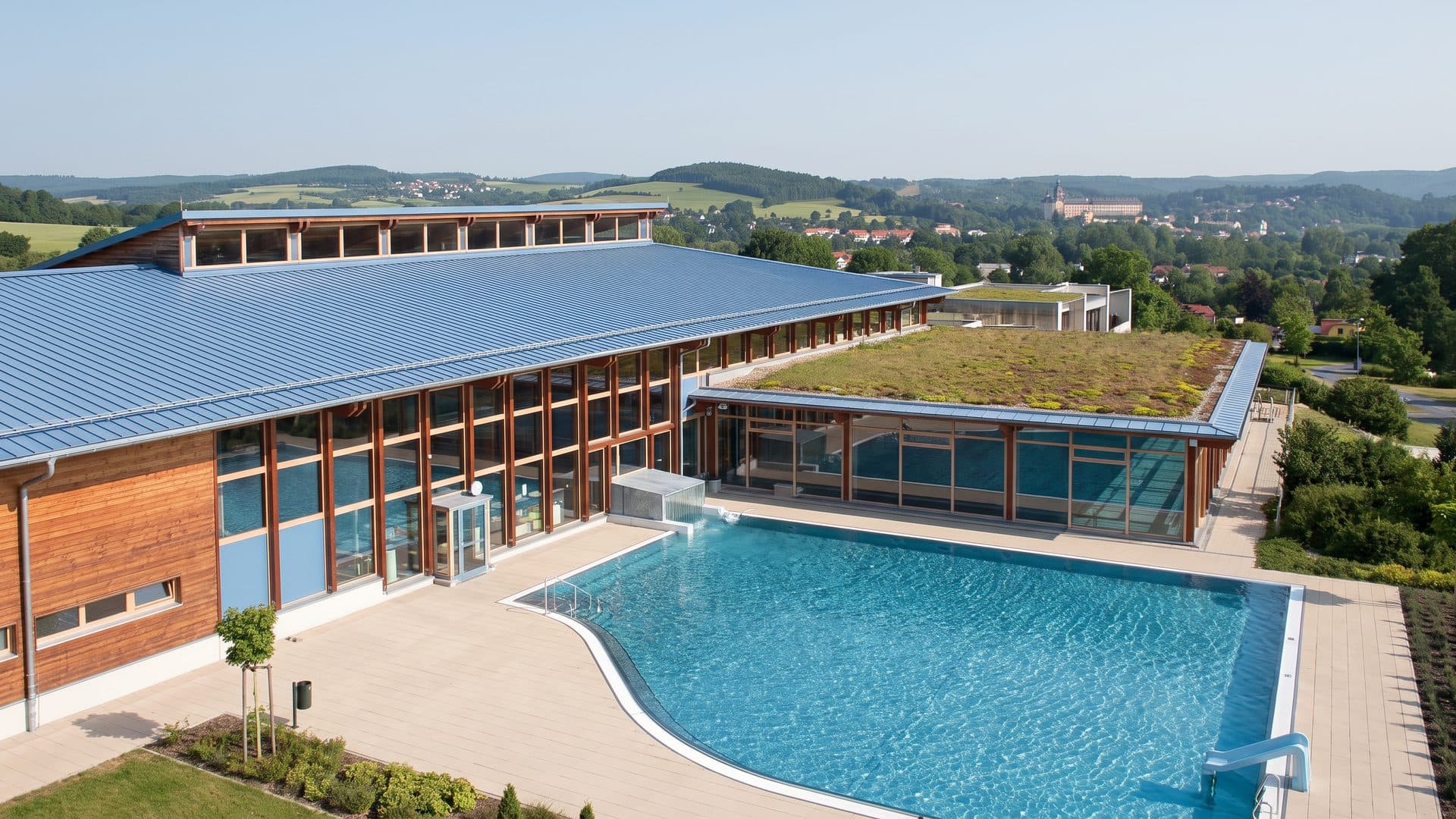 The timber-clad building of the Saalemaxx with its outdoor pool in front and the hills behind