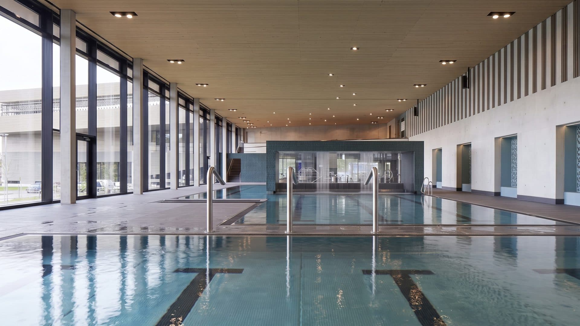 The indoor lane pool of the Schlossbad Neumarkt with water jets beside a tall glass wall