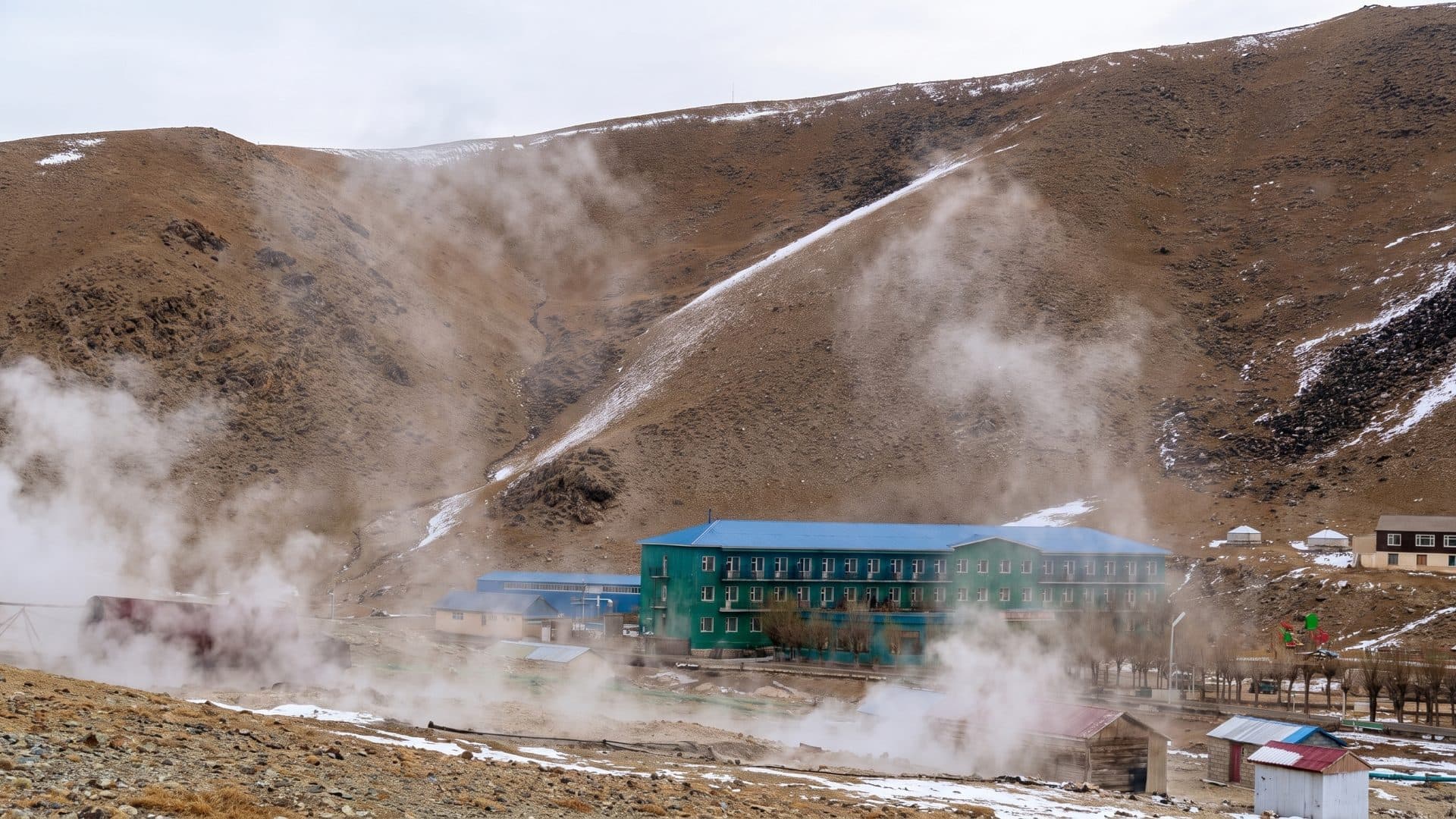 The steaming hillside at Shargaljuut, with the low buildings of the resort at its foot