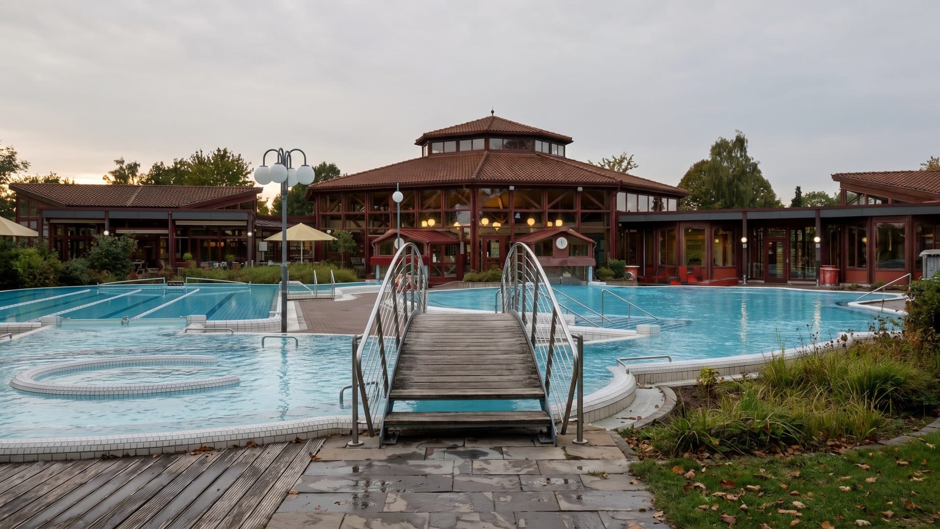 The pavilion and outdoor pools of Sonnenhof-Therme in Bad Saulgau, with a footbridge over the water.