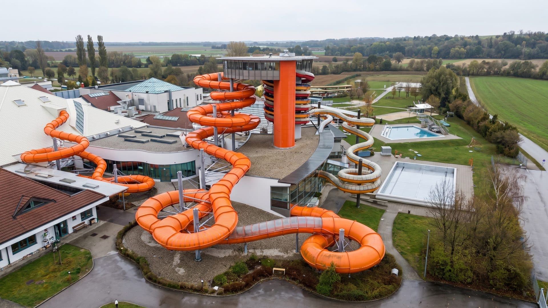 Sonnentherme Lutzmannsburg from the air: orange water slides looping beside the bath halls and outdoor pools.