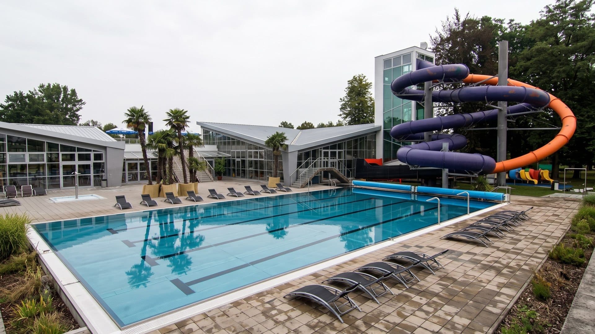 The outdoor lane pool of the Spa & Aquapark with a purple and orange slide tower and palms