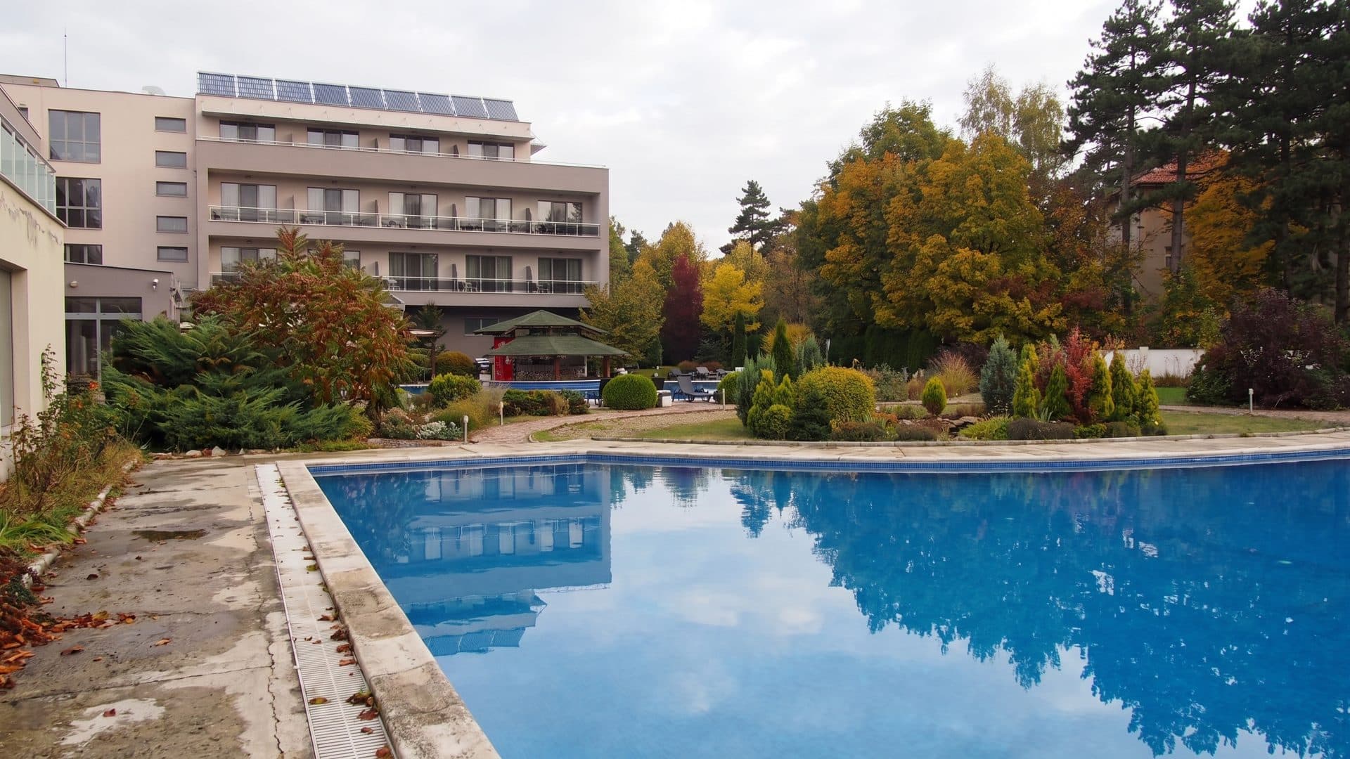 The outdoor pool below the wing of Spa Hotel Ata in Varshets, with autumn trees around it