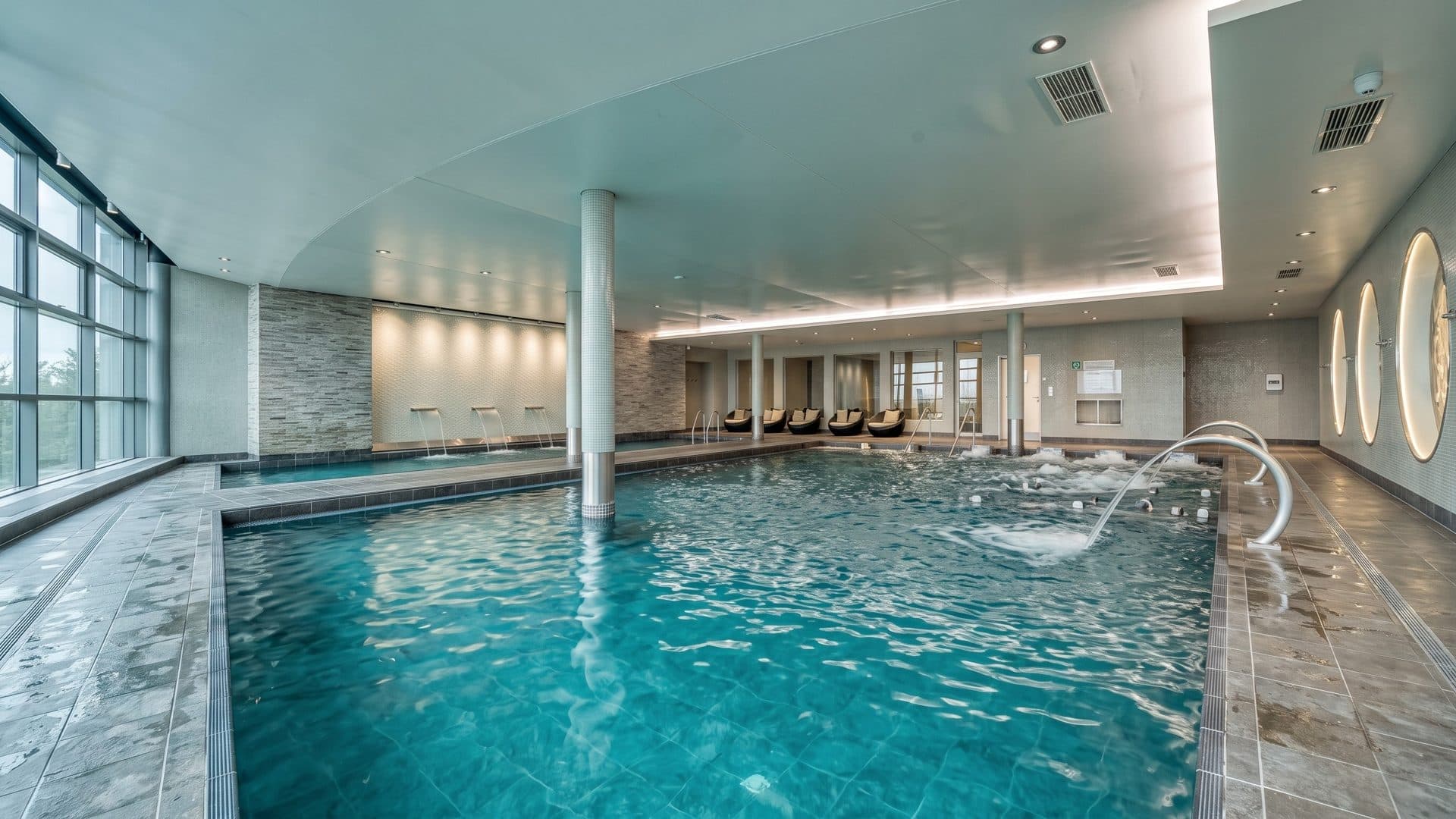 The indoor seawater pool of the Val Andre thalasso resort with water jets and round mirrors on the wall