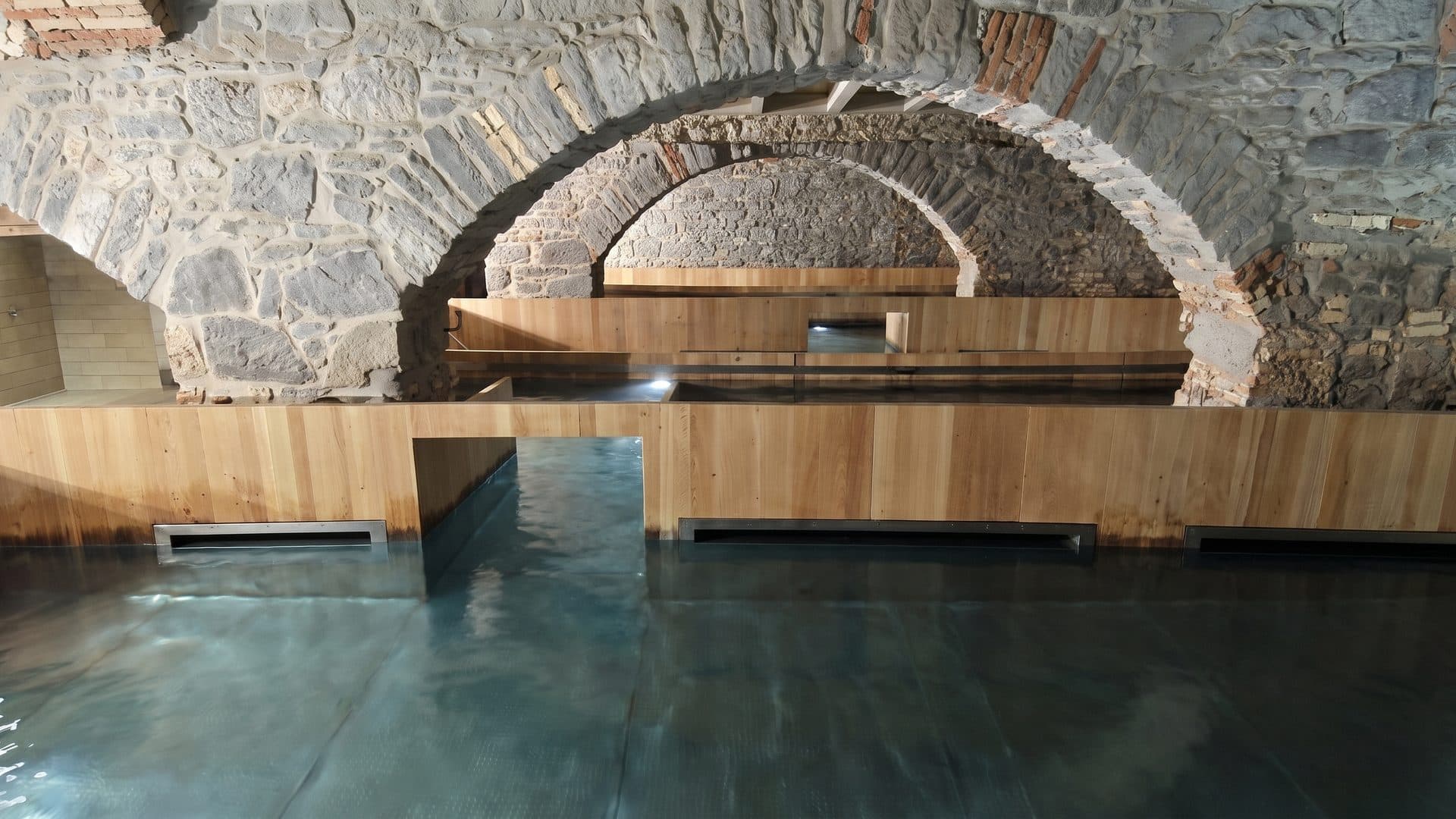 The vaulted stone thermal bath with its water running away beneath the arch