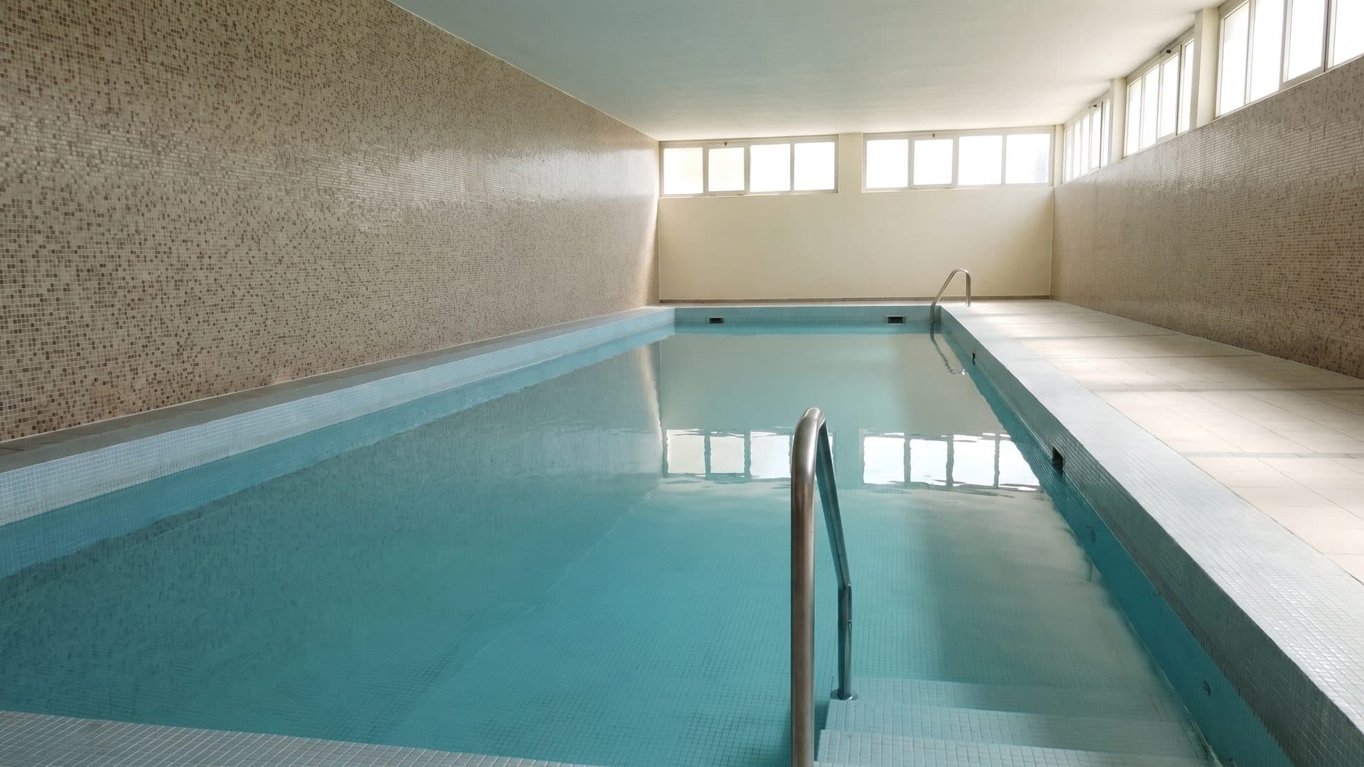 The indoor pool of the Stabio thermal baths below its band of high windows