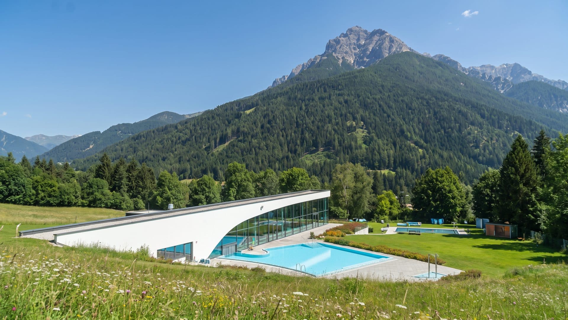 The StuBay with its sweeping white roof and outdoor pool on the meadow below the mountain
