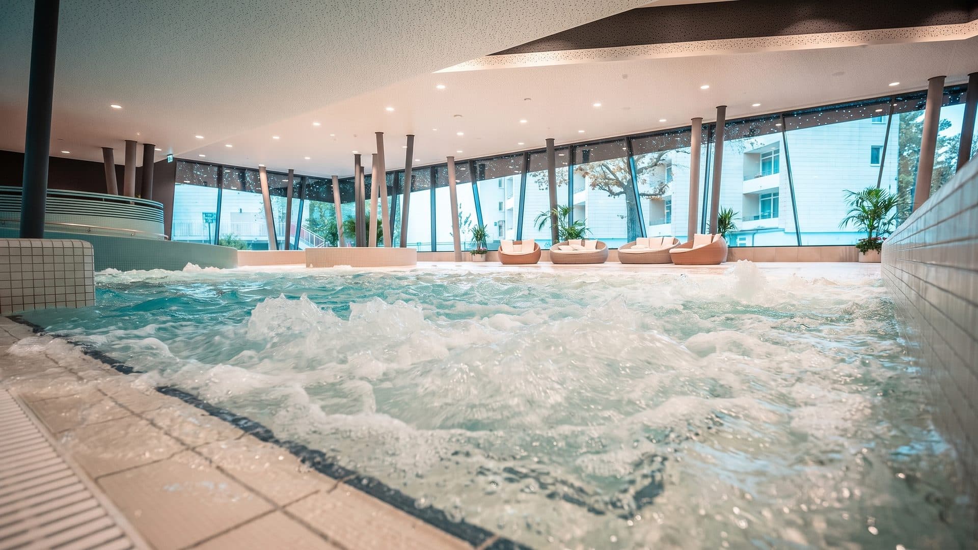 The bubbling indoor pool of the subtropical bathing paradise below its window wall