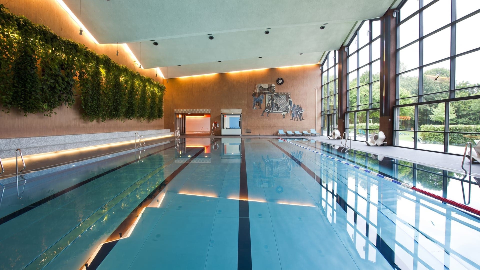 The swimming hall of the Suedbad, its terracotta walls hung with greenery beneath tall steel-framed windows.